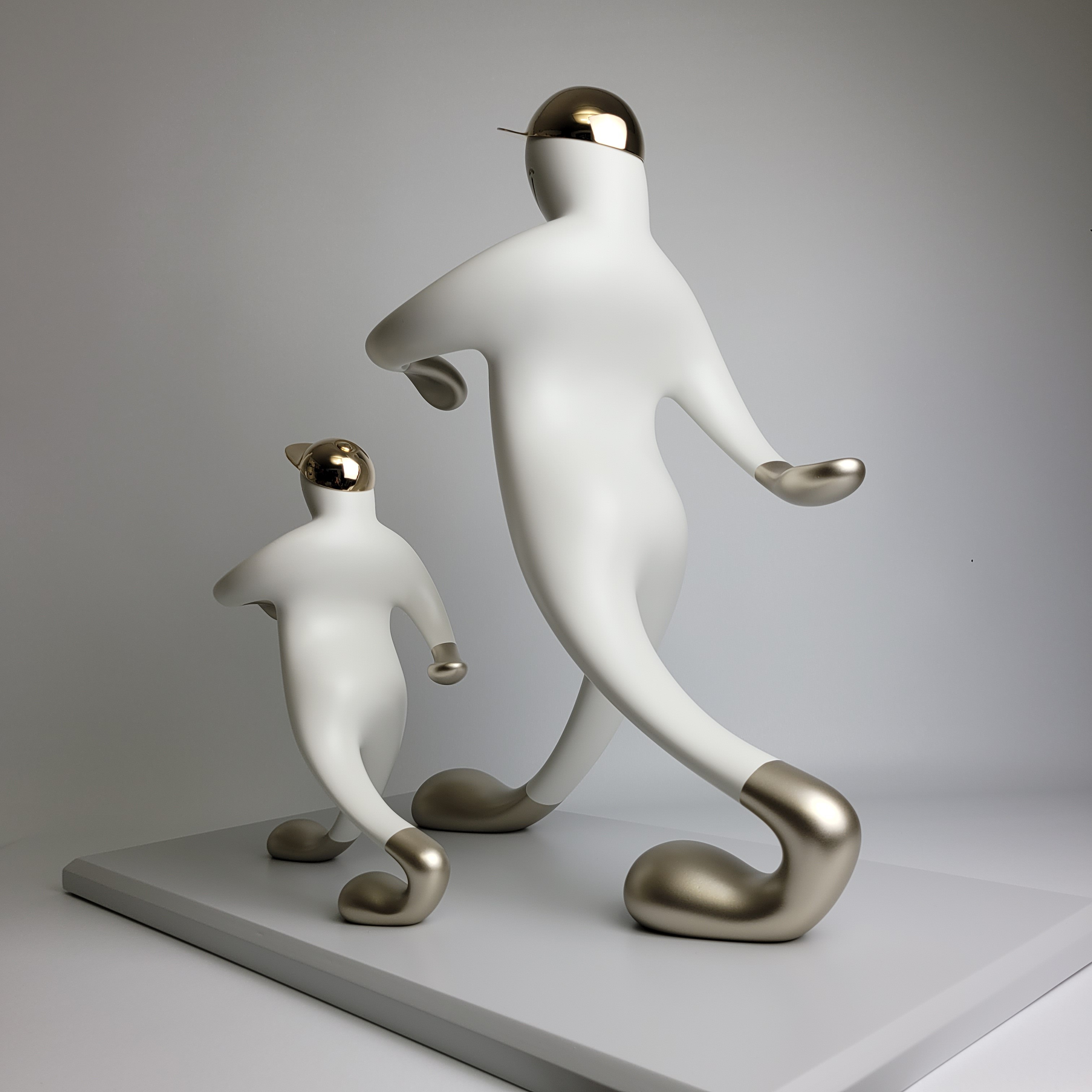 A playful sculpture of two figures in a matching pose, featuring smooth white forms with metallic accents.