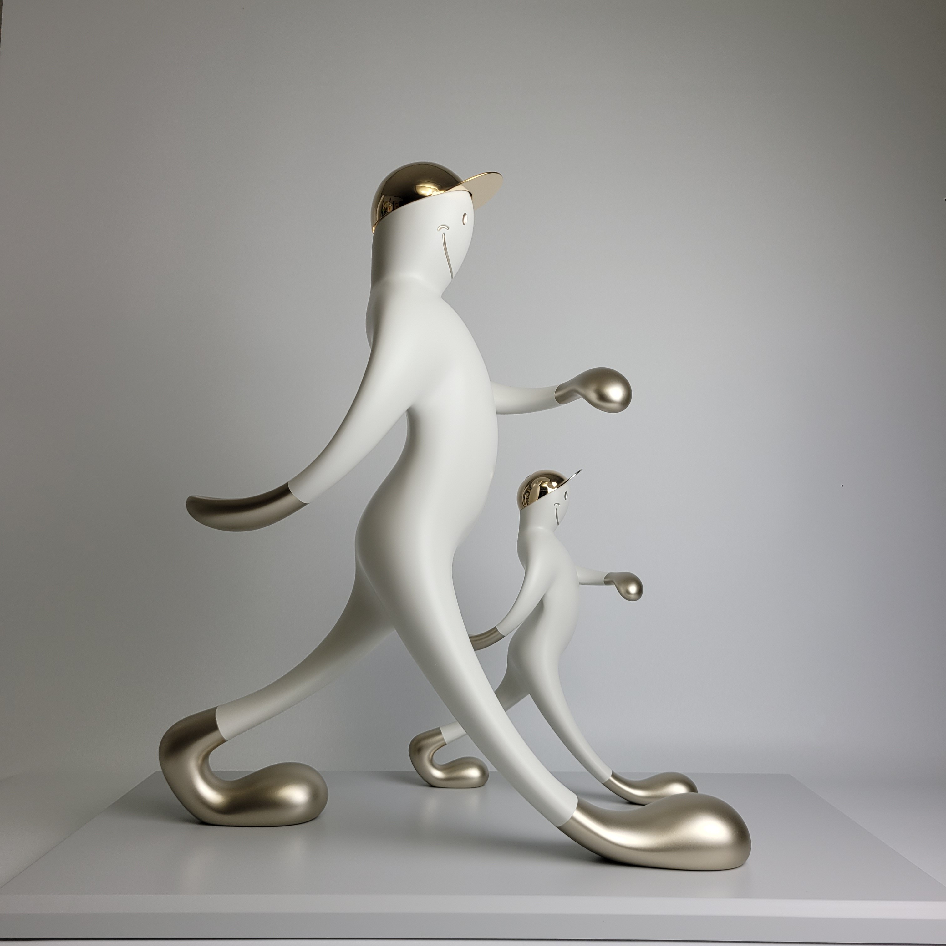 A playful sculpture of two figures in a matching pose, featuring smooth white forms with metallic accents.