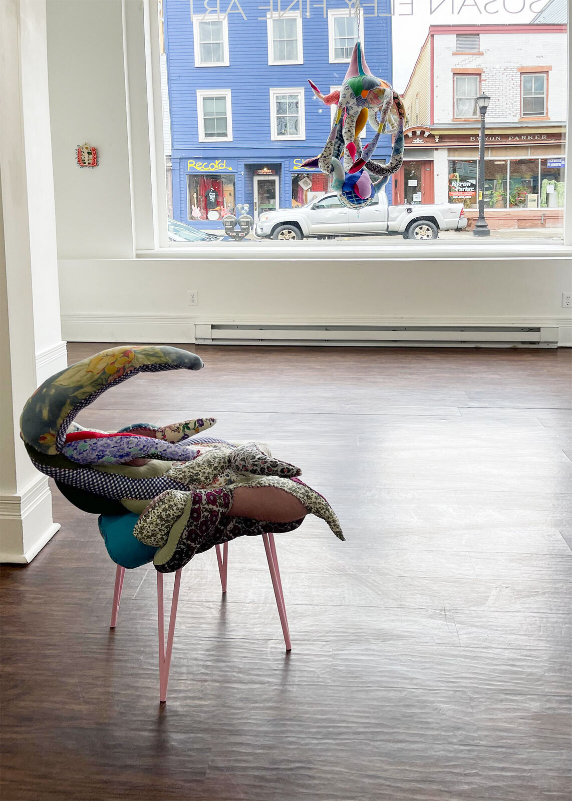 A whimsical chair with a patchwork quilt seat and slender pink legs.