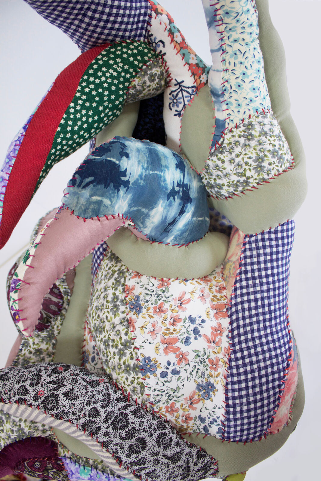 A whimsical chair with a patchwork quilt seat and slender pink legs.