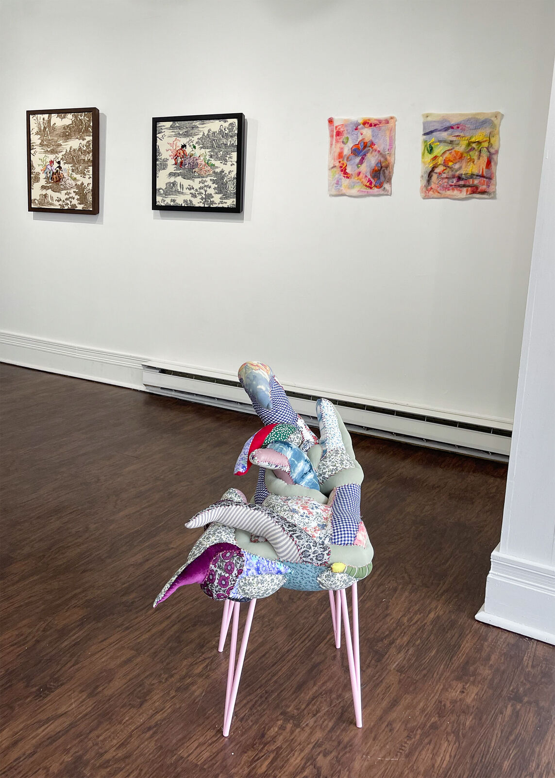 A whimsical chair with a patchwork quilt seat and slender pink legs.