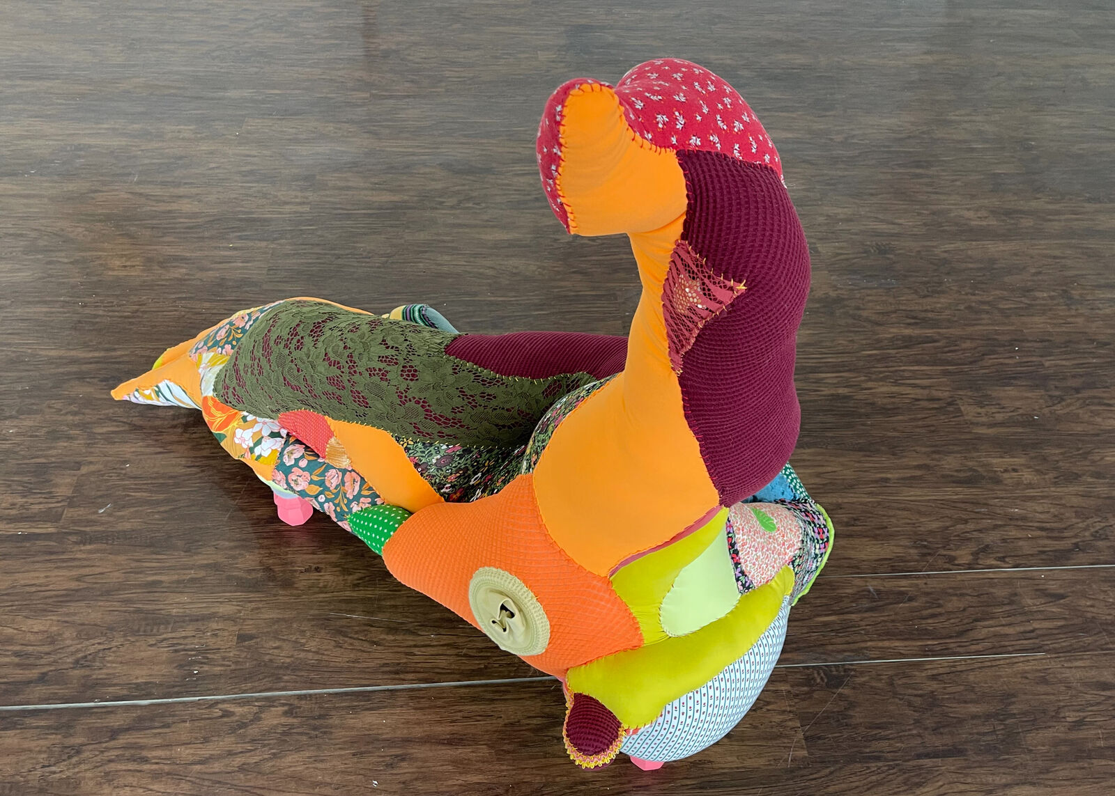 A colorful, patchwork-style lounge chair shaped like a reclining figure with an upward-extended leg.