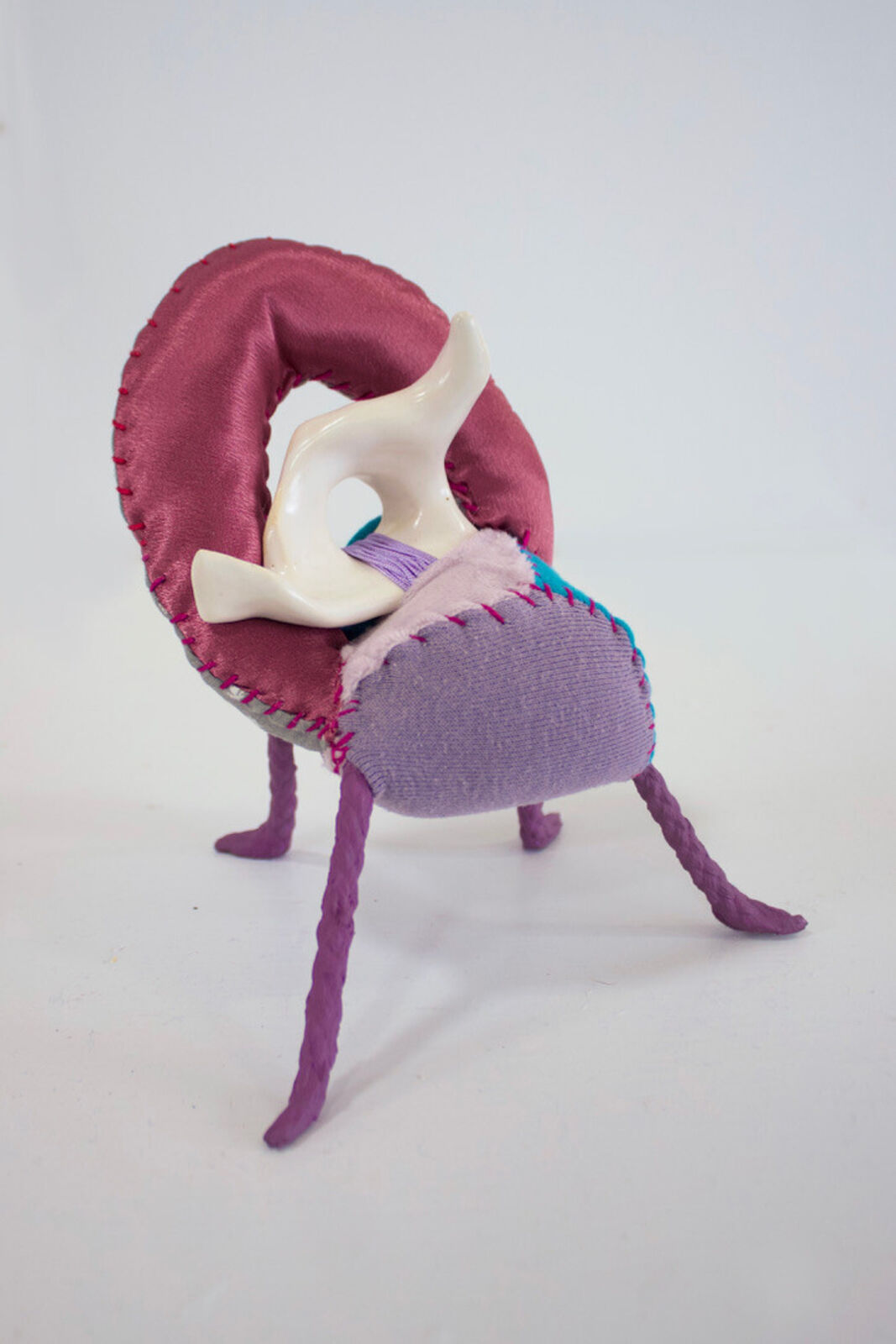 A whimsical, patchwork chair with braided legs and a ceramic backrest.