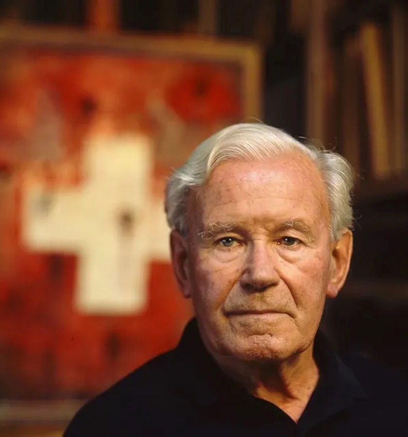 A black and orange painting of a man standing in front of a table.