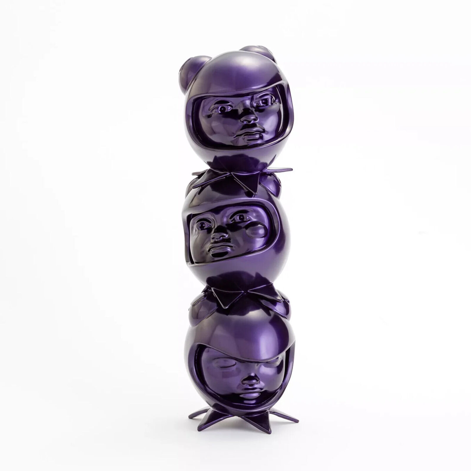 A stack of three purple ceramic figurines on a white background.