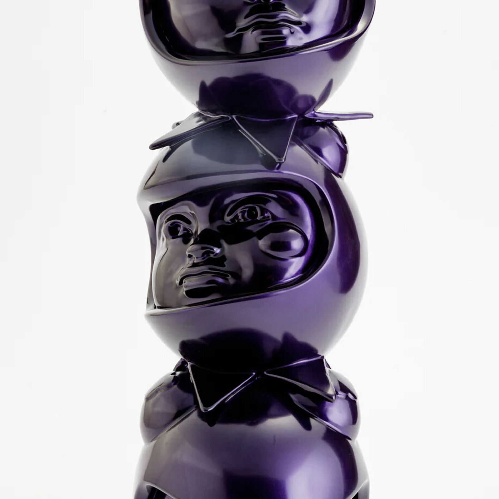 A stack of three purple ceramic figurines on a white background.