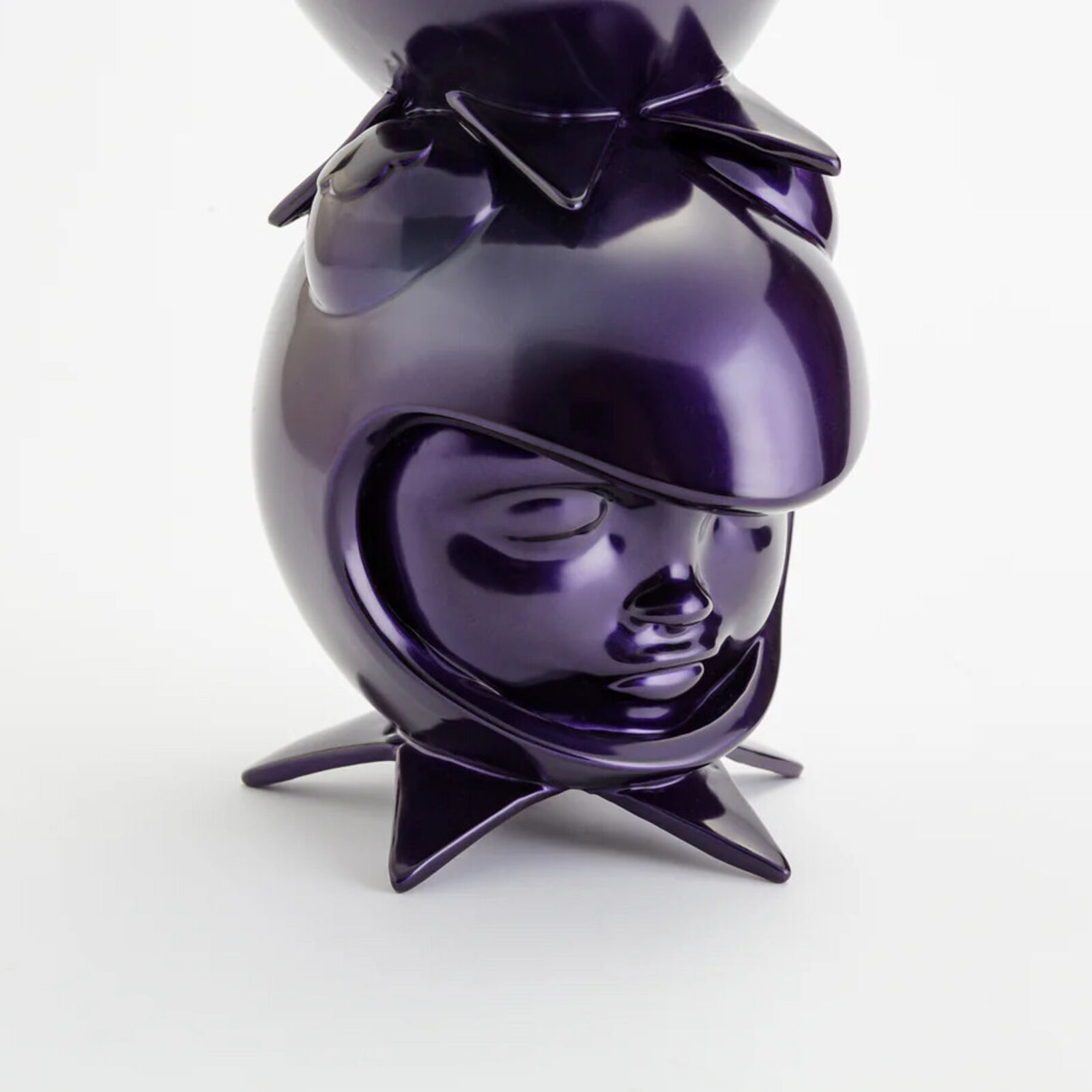 A stack of three purple ceramic figurines on a white background.