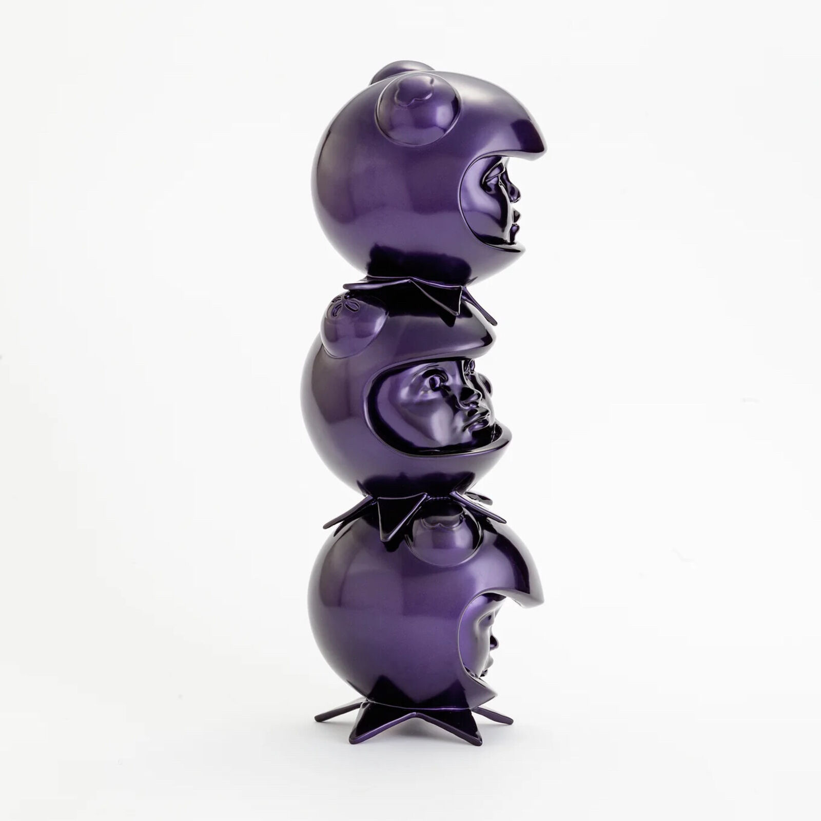 A stack of three purple ceramic figurines on a white background.