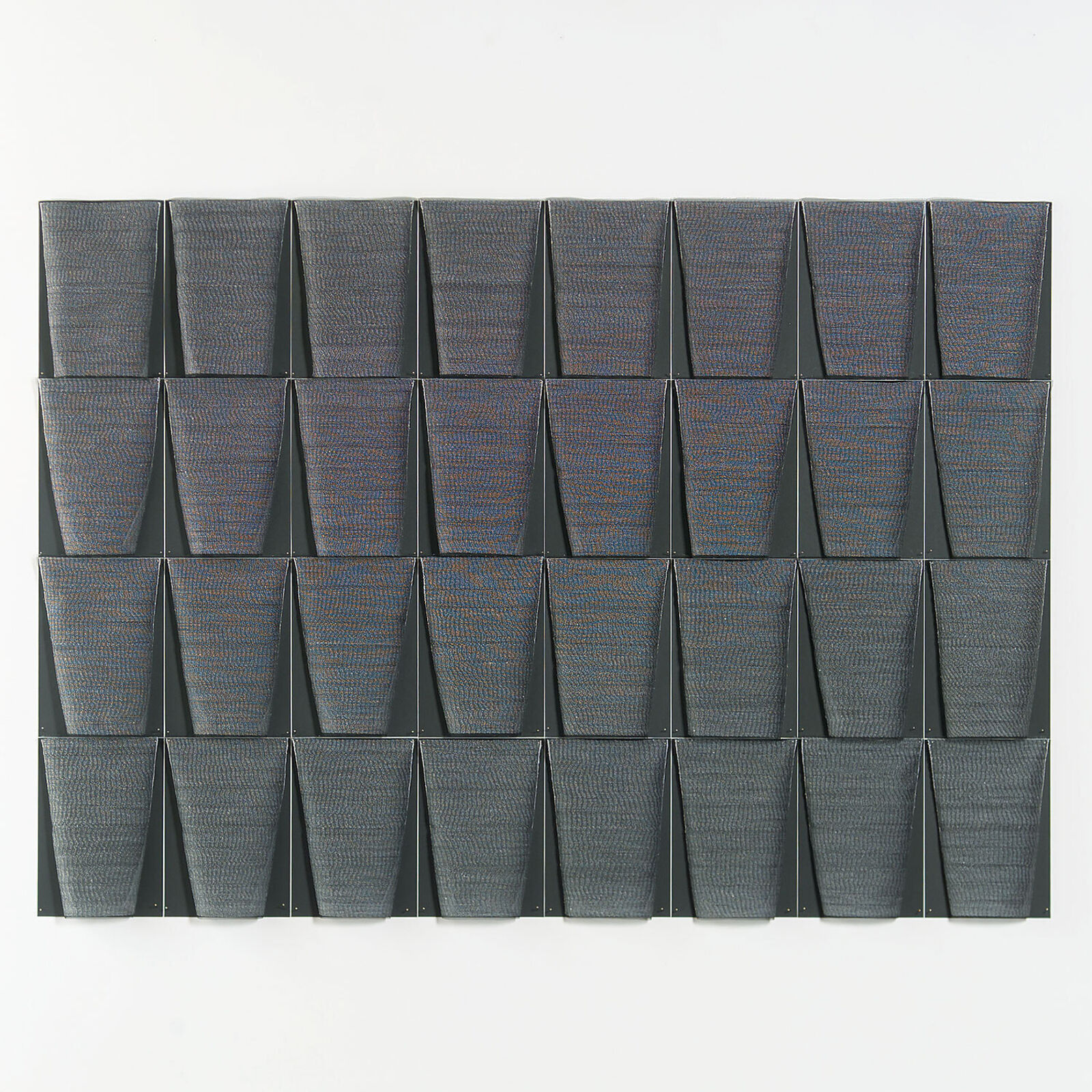A framed textile grid of grey woven cups on a white wall.