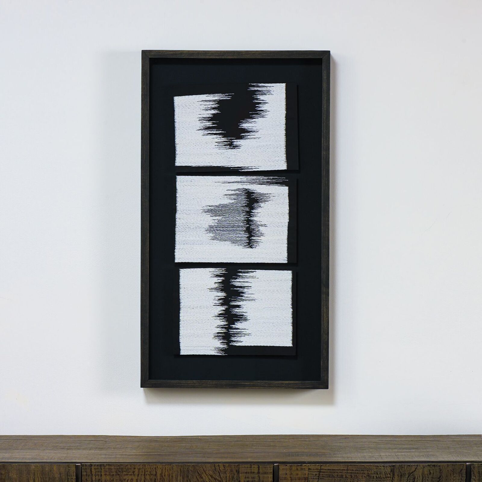 A black and white painting hanging on a wall above a dresser.