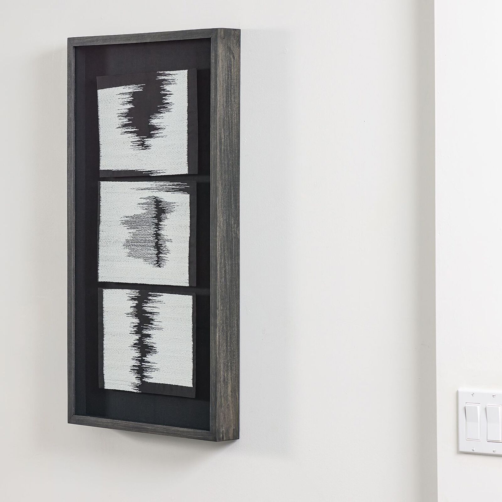 A black and white painting hanging on a wall above a dresser.