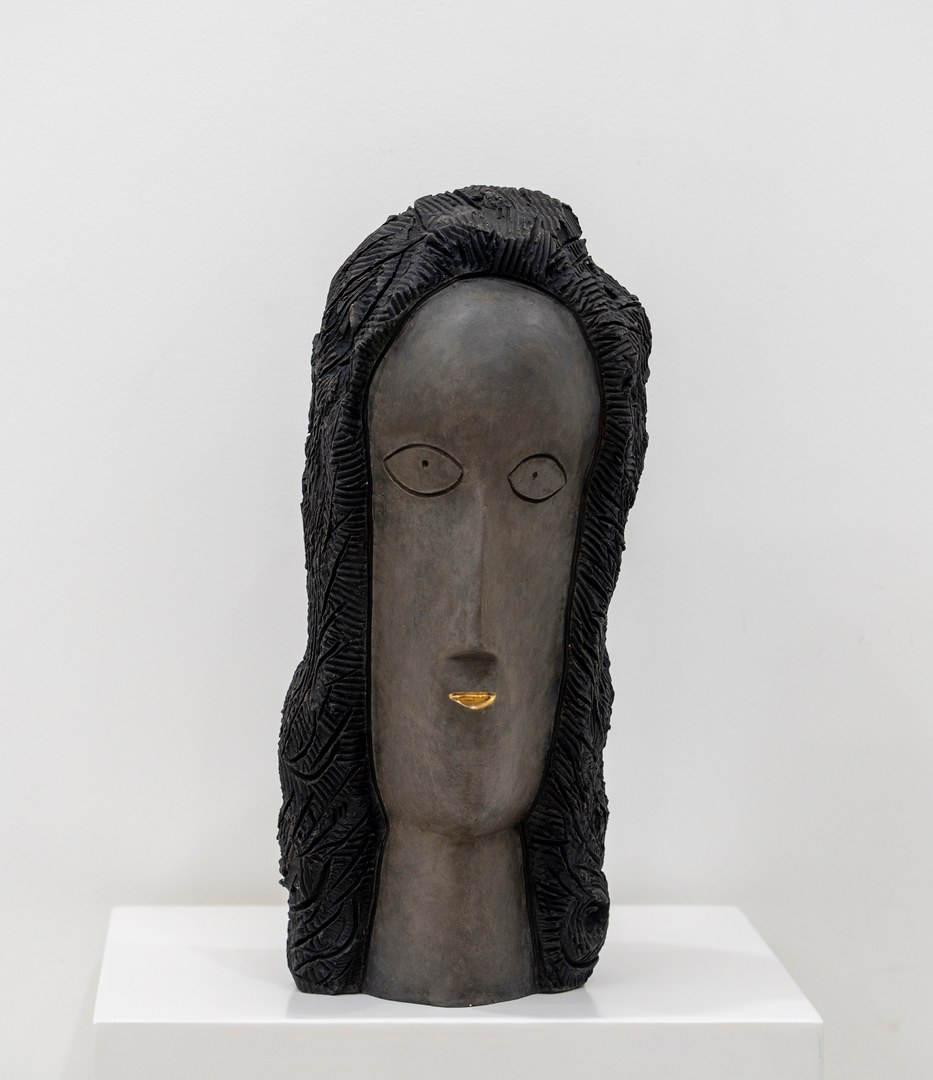 A sculpture of a woman's face on a white pedestal.
