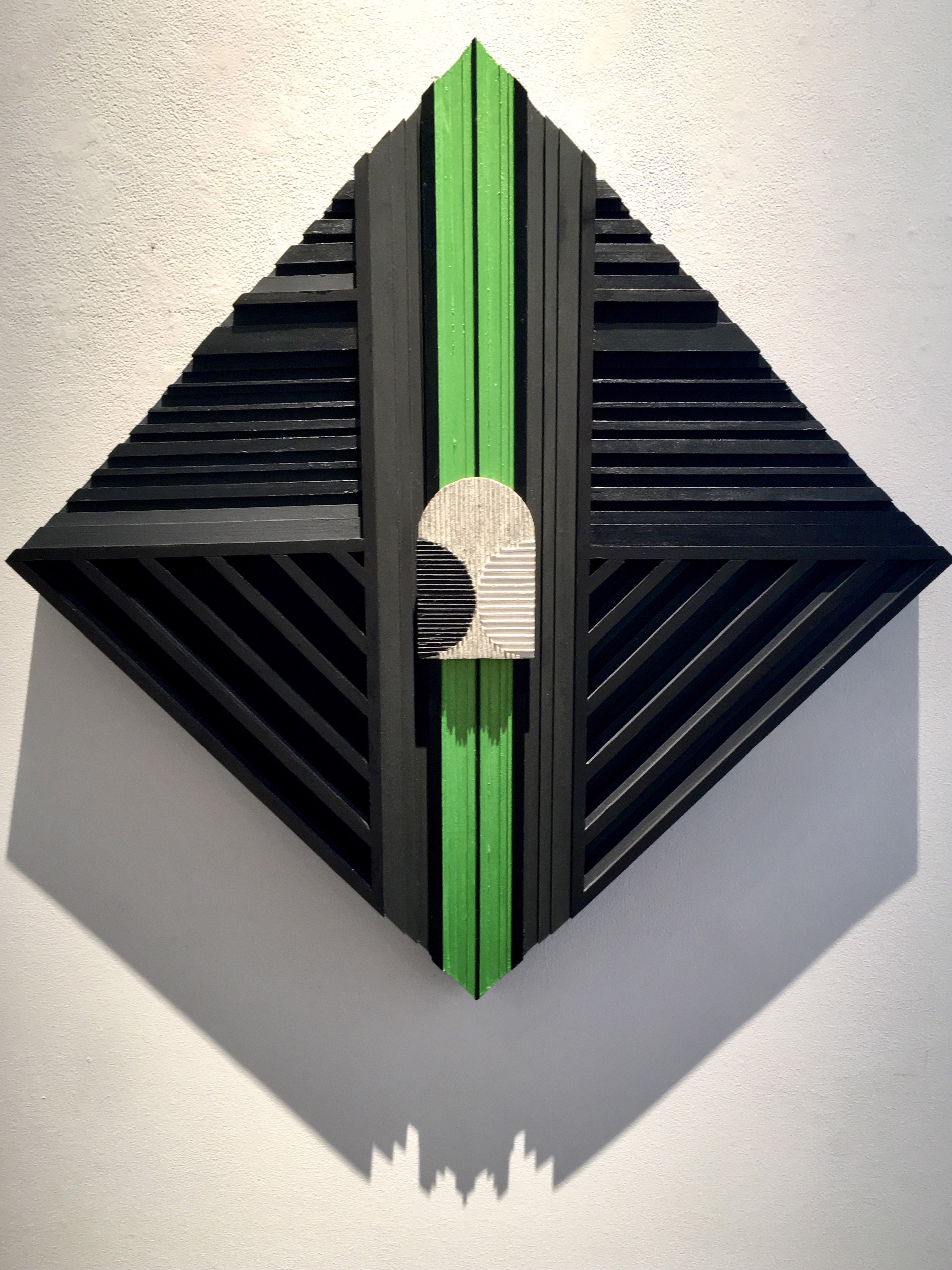 A black and green wall hanging on a white wall.