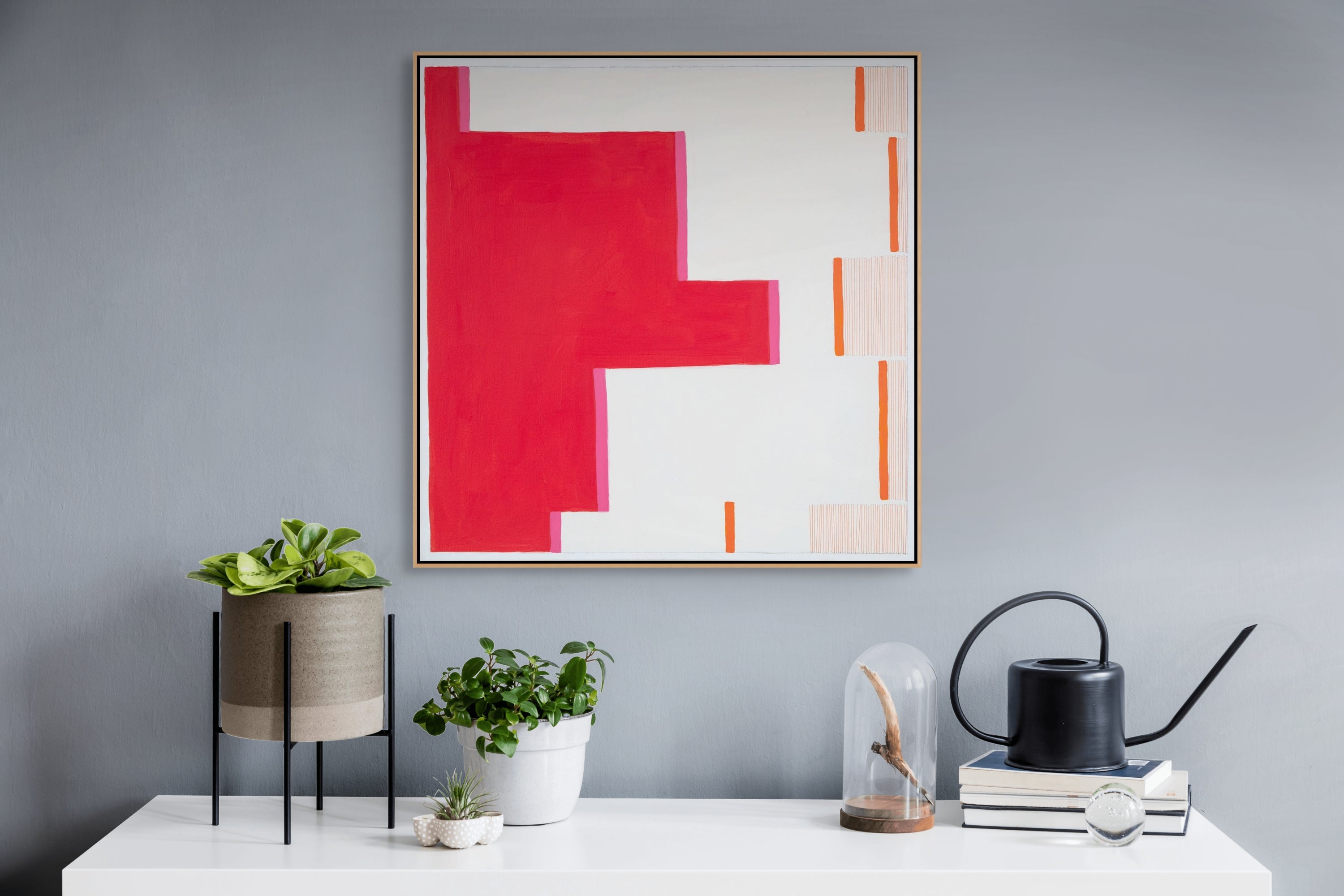 A painting on a white wall with a red and orange design.