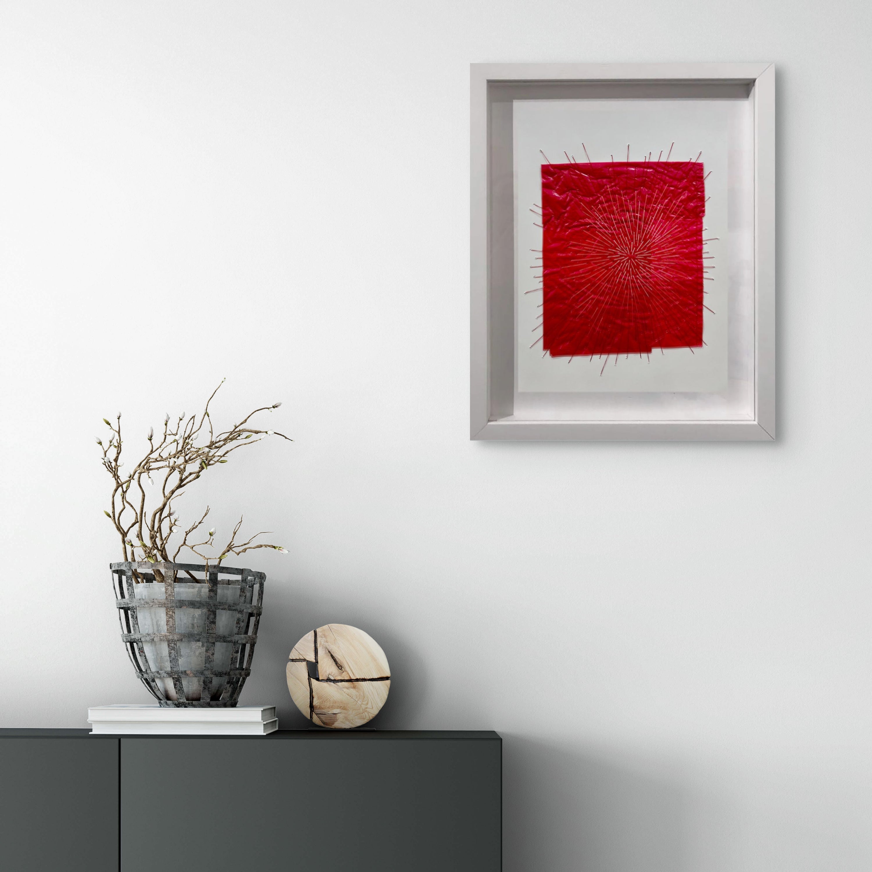 A picture of a red piece of art in a white frame.