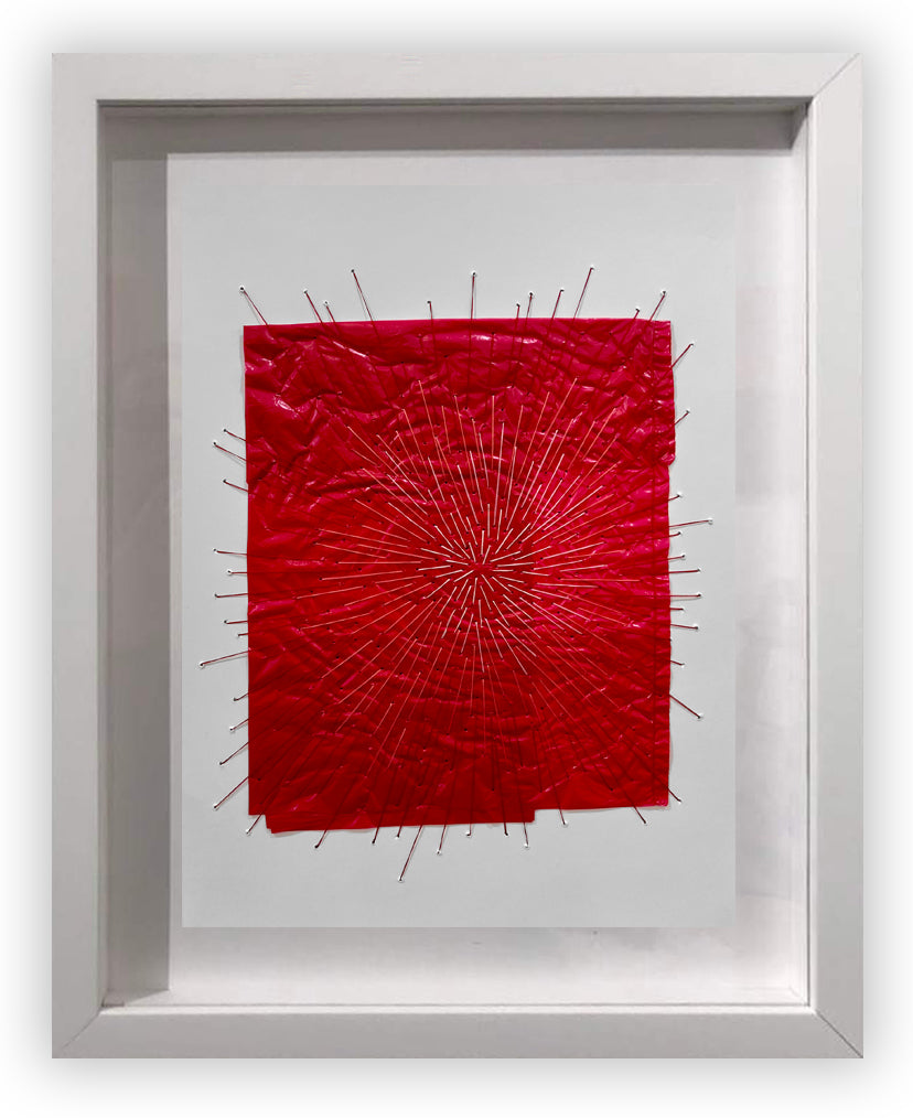 A picture of a red piece of art in a white frame.