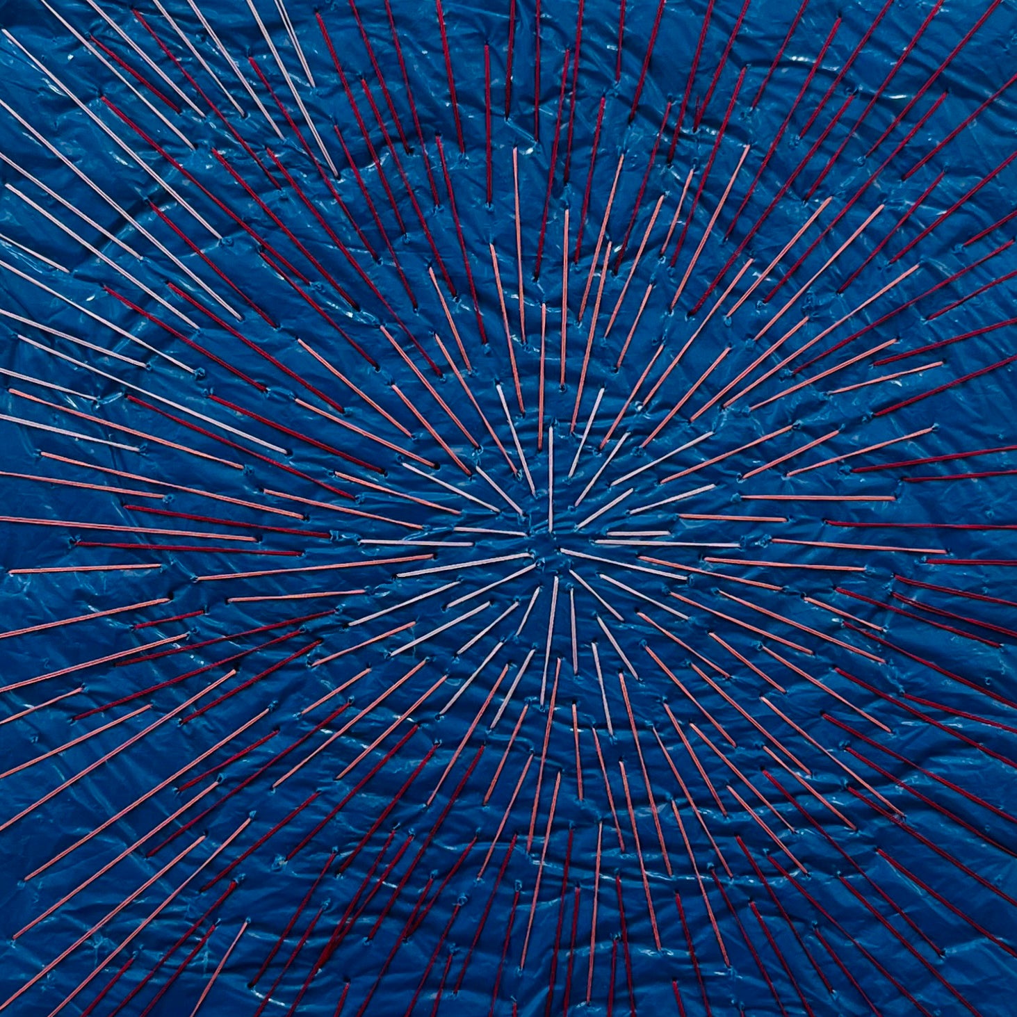 A picture of a blue and red string art in a white frame.