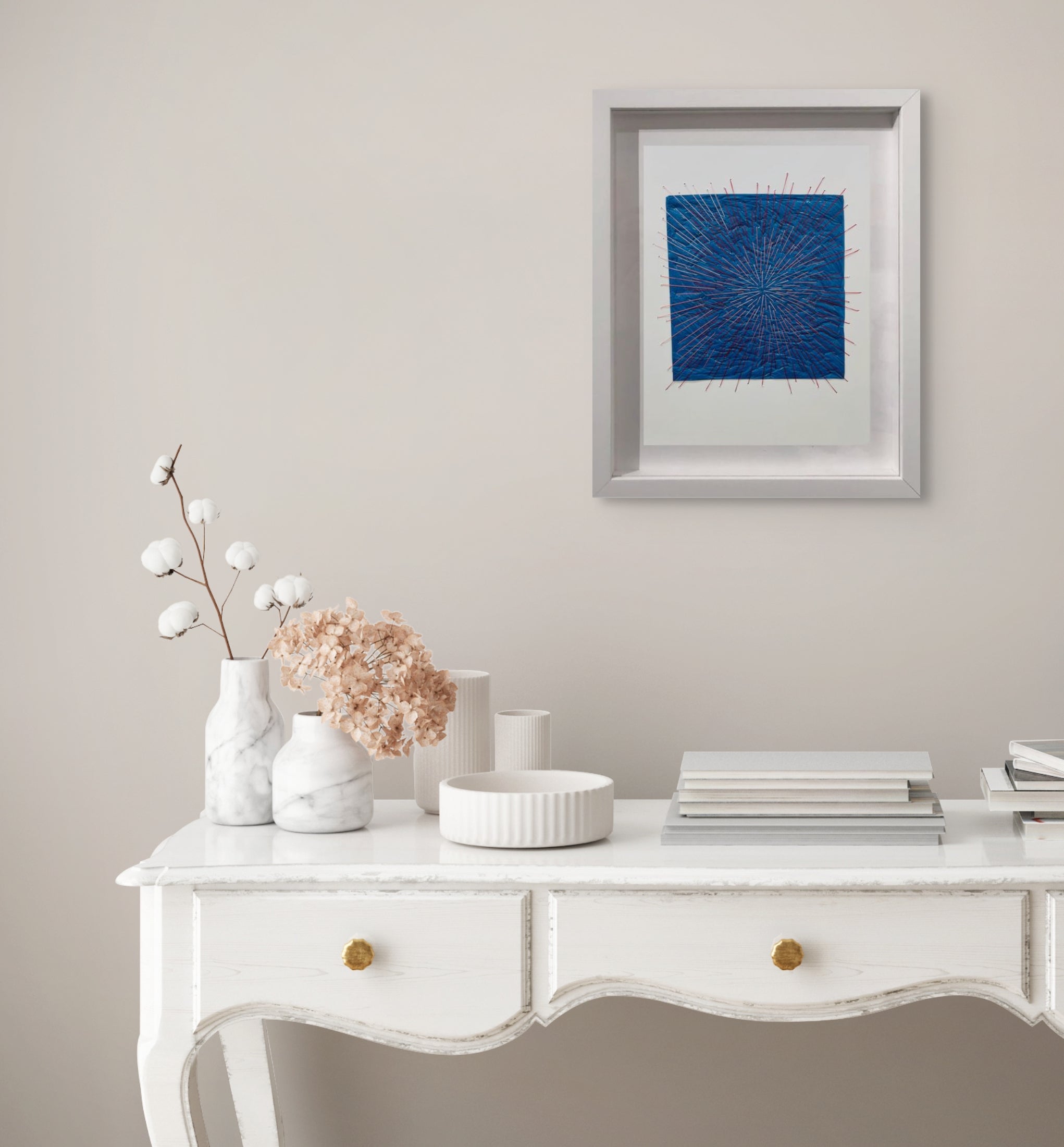 A picture of a blue and red string art in a white frame.