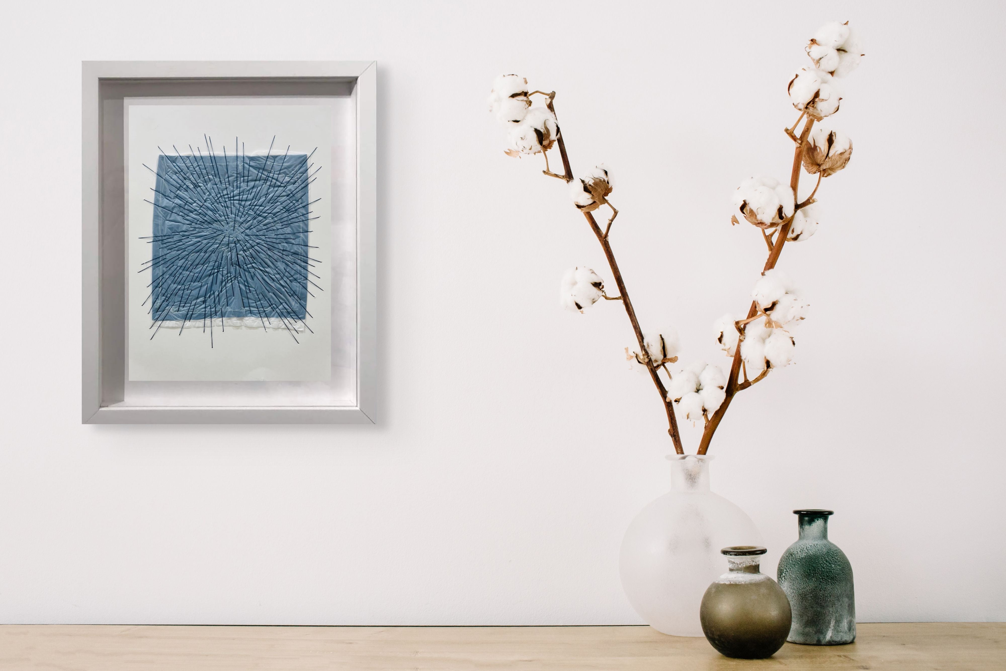 A picture of a blue and white abstract painting in a white frame.