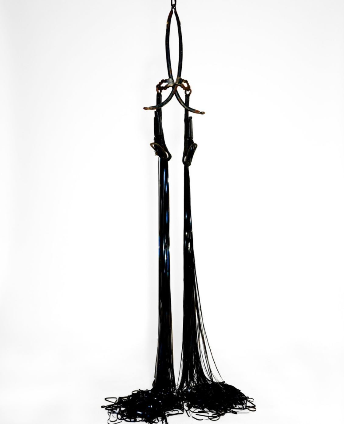 A minimalist sculpture featuring a suspended metal frame with cascading black threads.