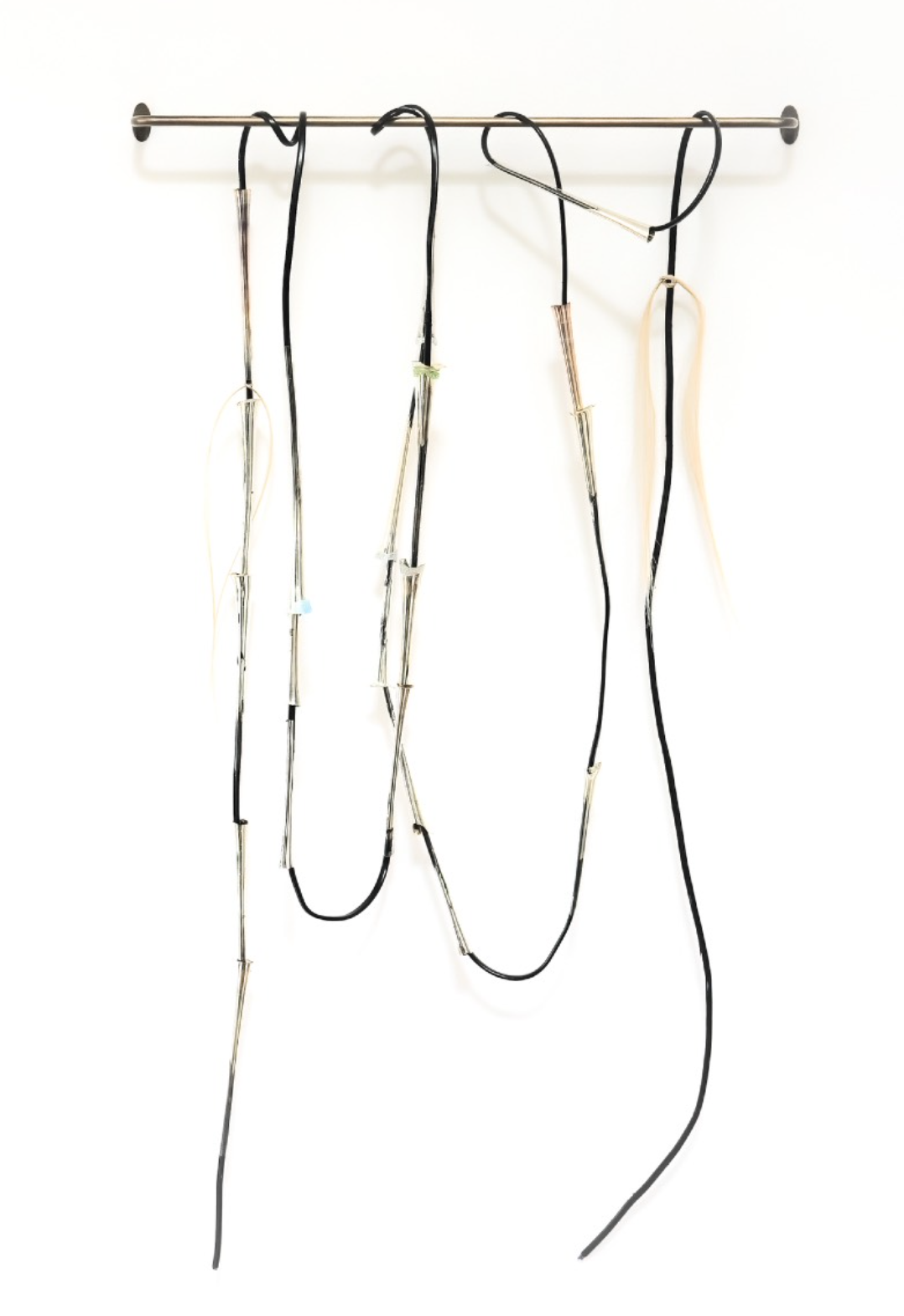 A minimalist sculpture featuring hanging wires and rods against a stark white background.