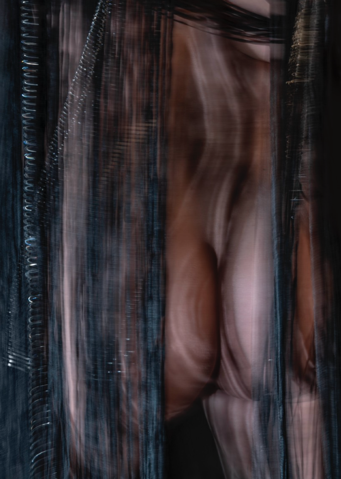A mysterious portrait of a figure viewed through sheer, dark fabric.