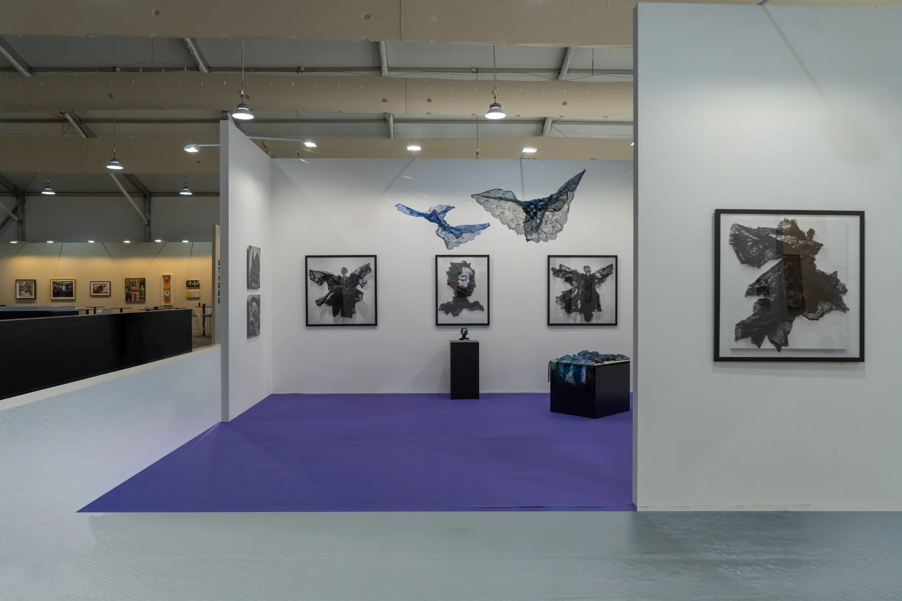 A framed artwork featuring a black, flowing fabric figure against a stark white background.