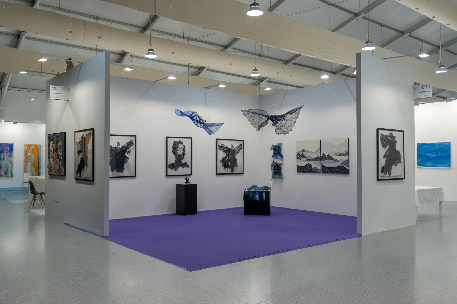 A framed black sculpture of a winged figure made from sheer, layered fabric against a stark white gallery wall.