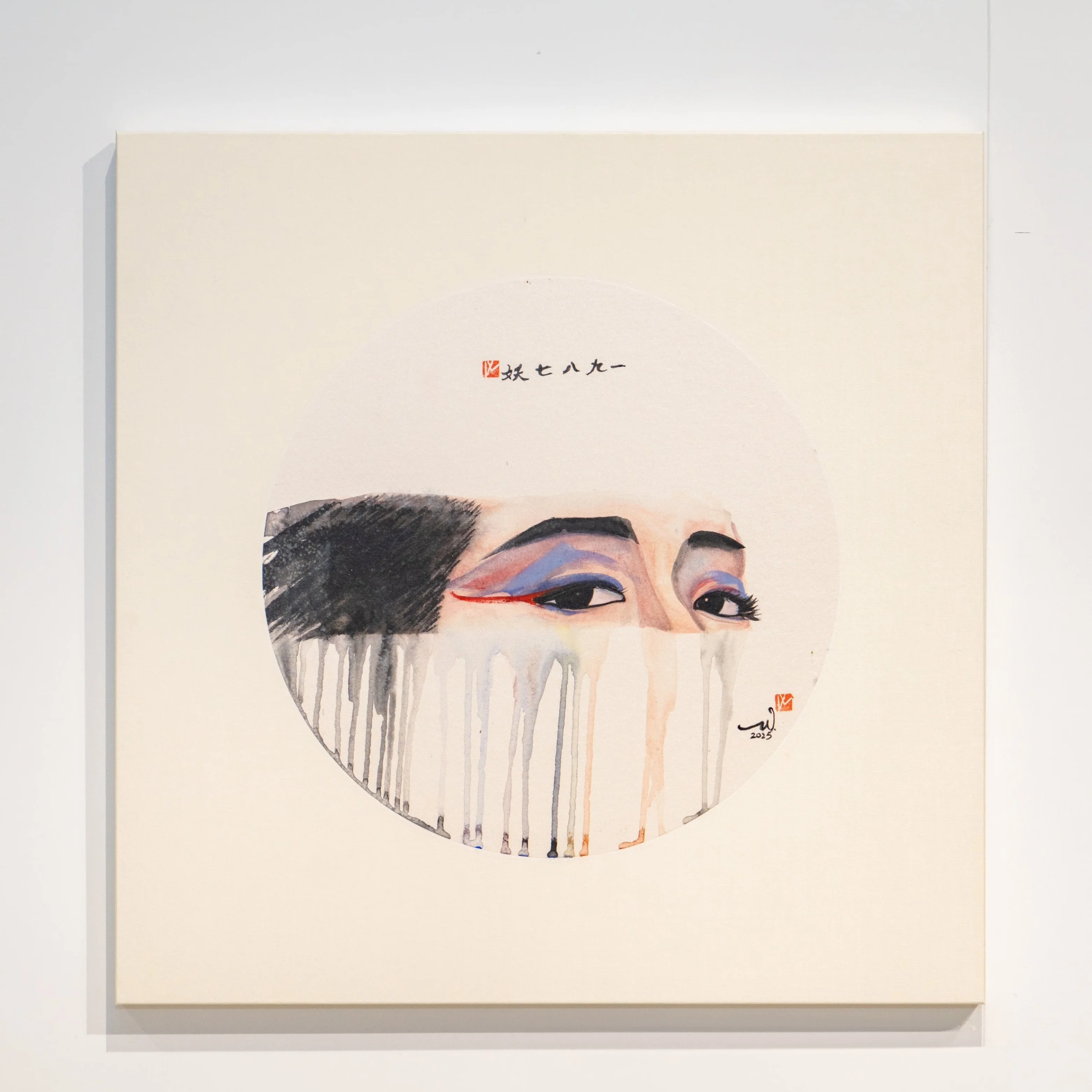 A minimalist gallery scene featuring a square artwork with an abstract face design.