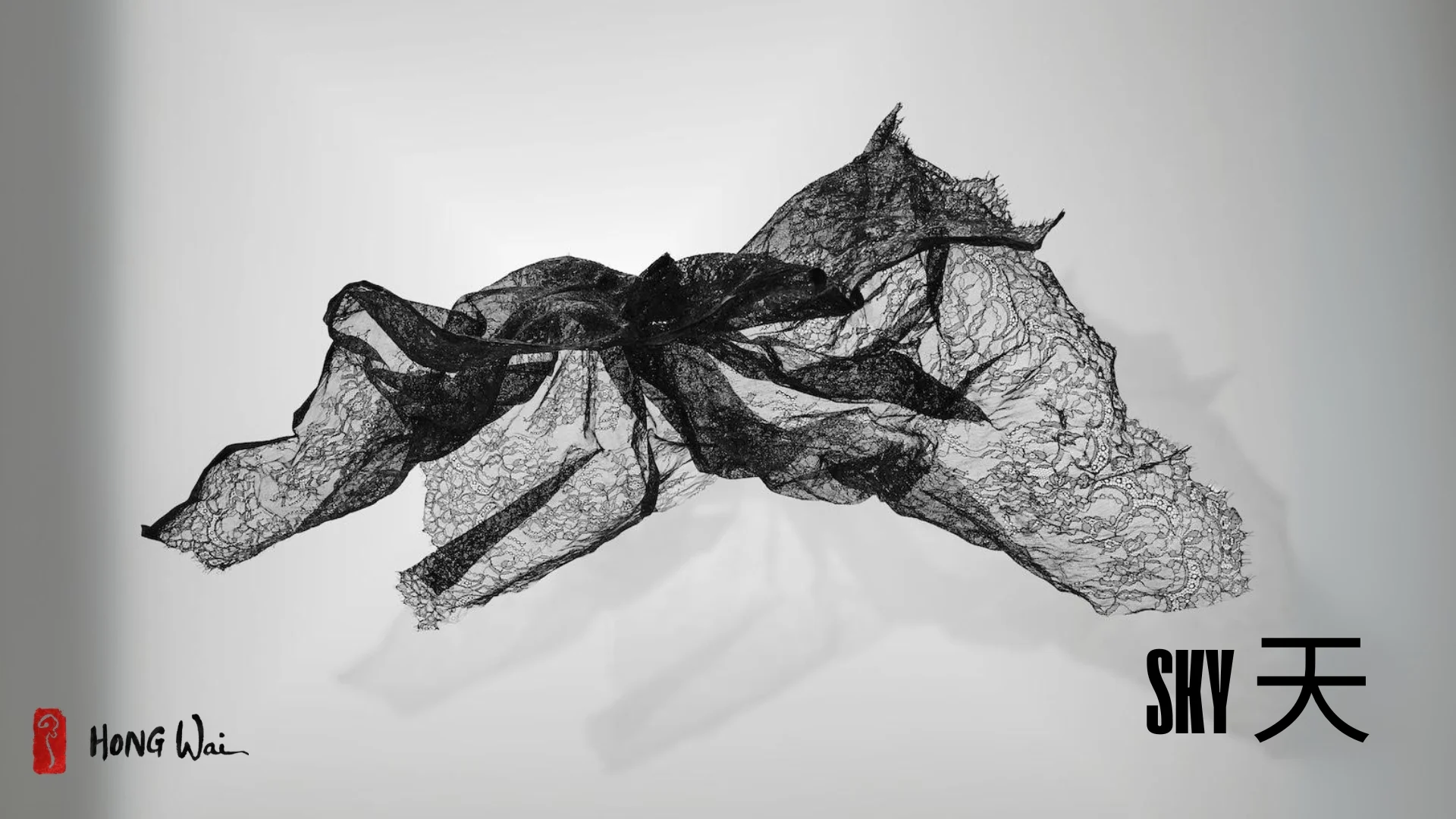 A solitary figure sits on a bench, gazing upward at floating black net-like sculptures against a stark white wall.