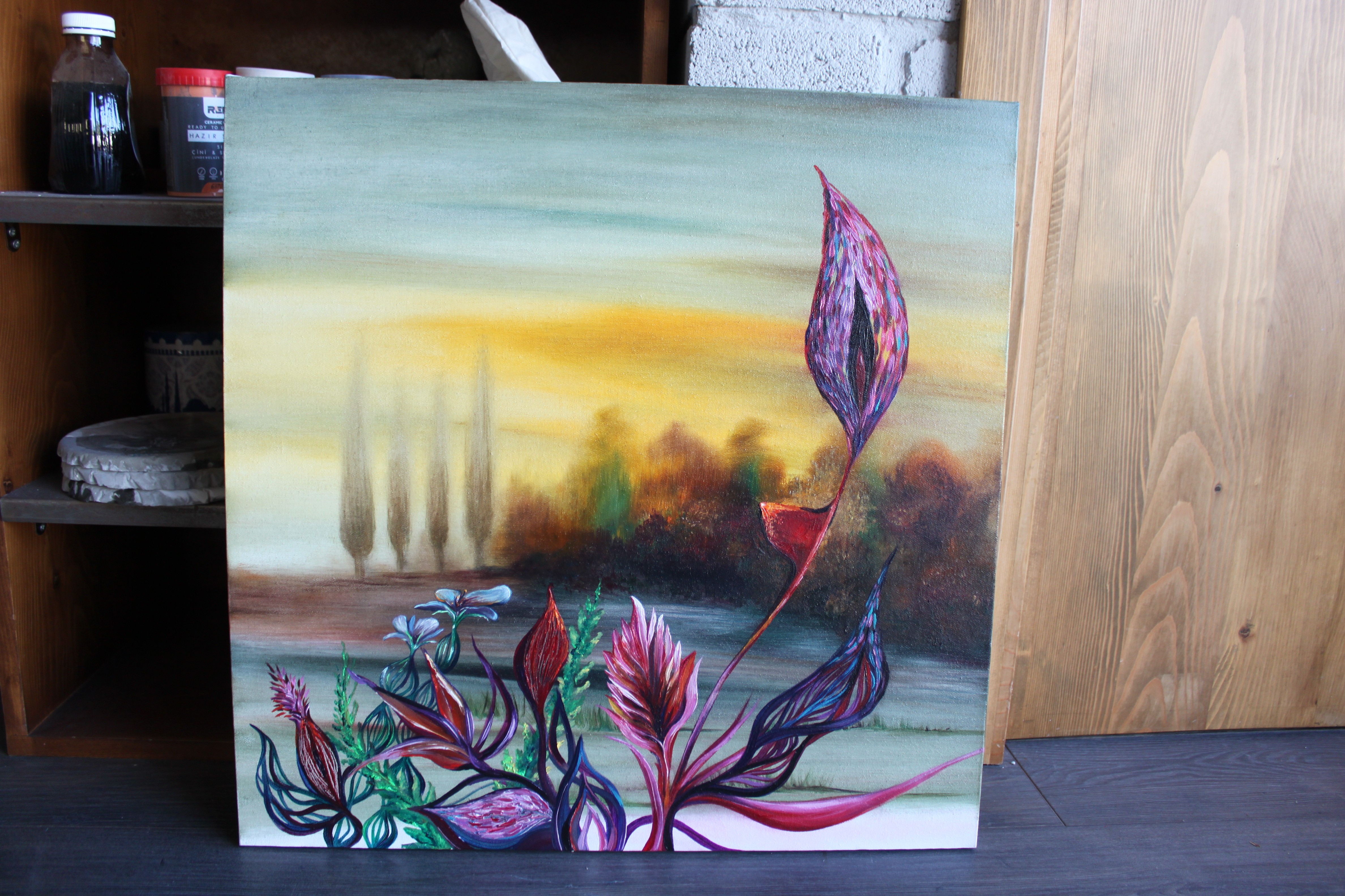 A painting on a wooden table in front of a shelf.