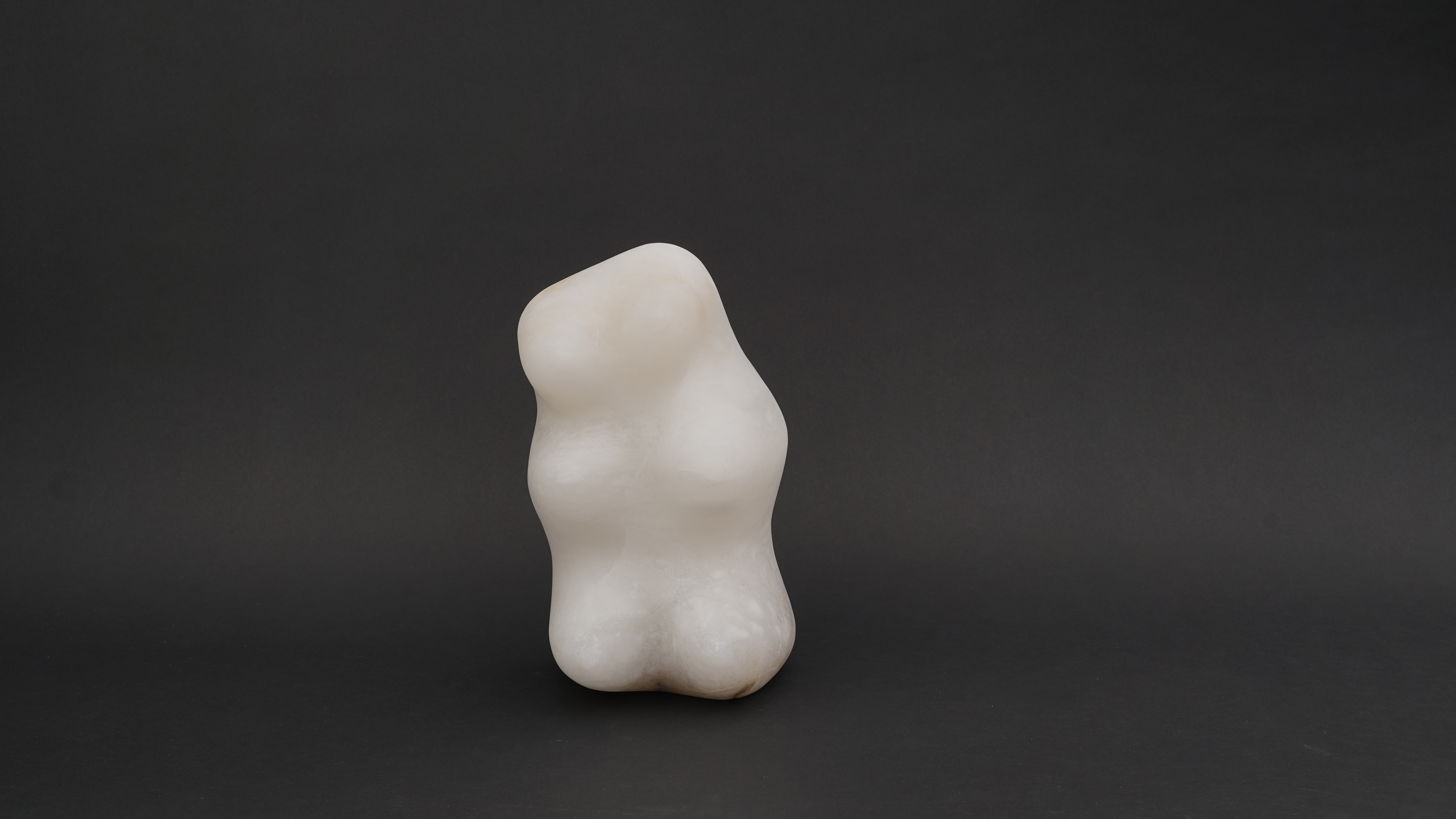 A white sculpture of a woman's torso on a black background.