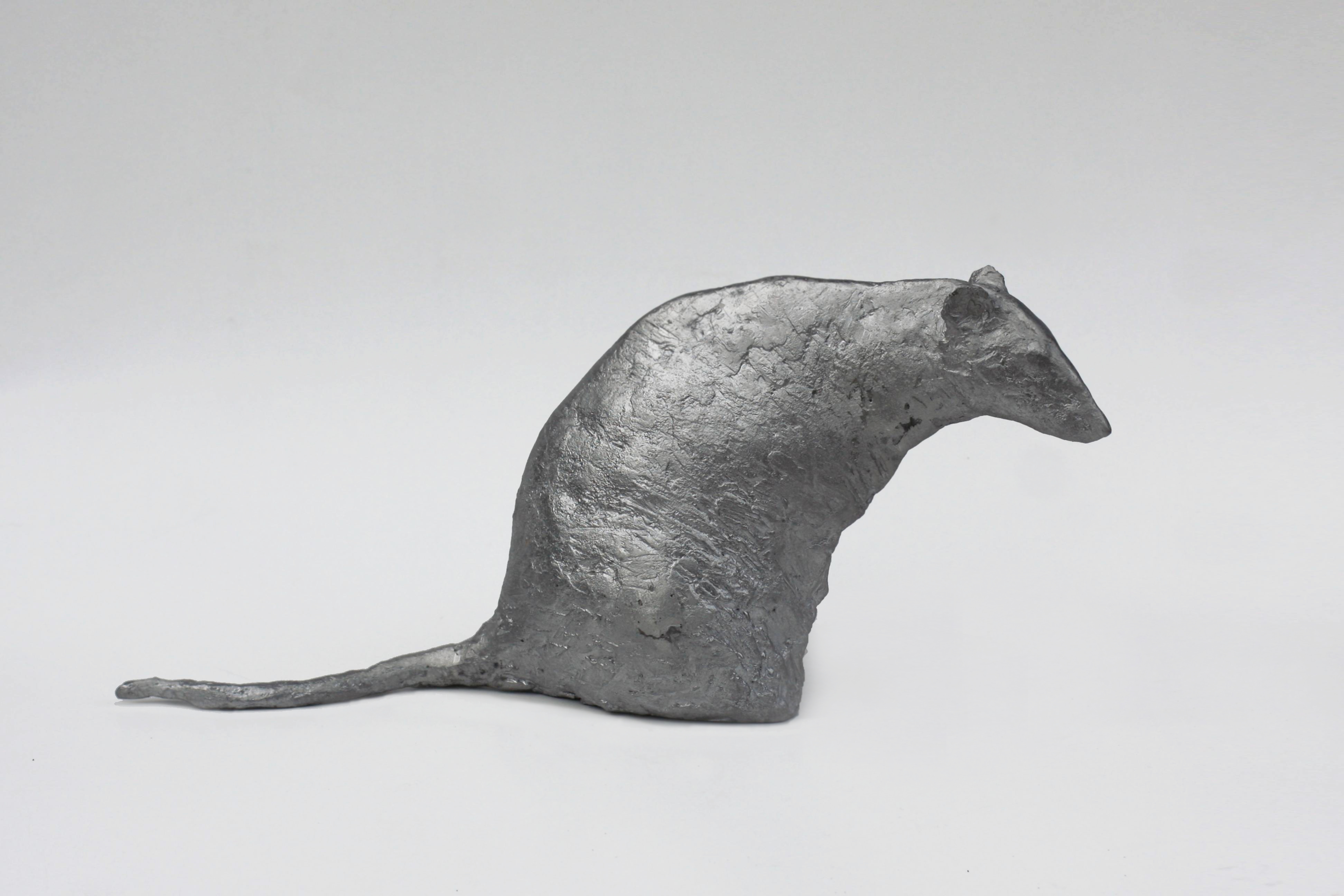 A metal sculpture of a rat on a white surface.