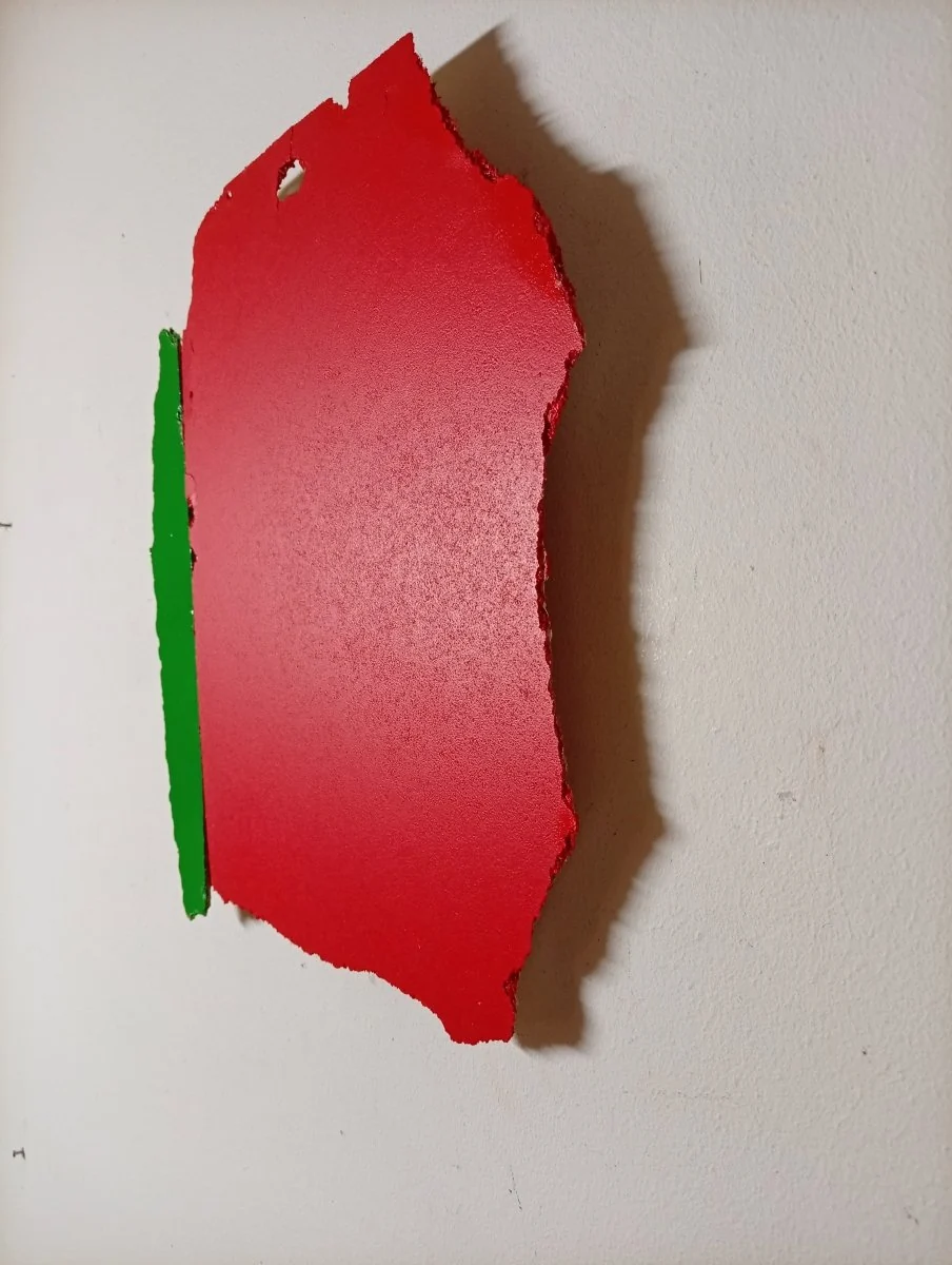 A bold, abstract composition featuring a red shape with a green vertical strip and a hole at the top.