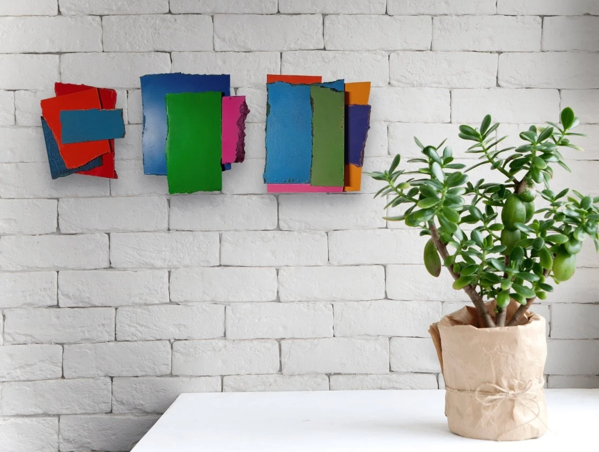 A layered composition of three rectangular paper sheets in blue, green, and pink against a white background.