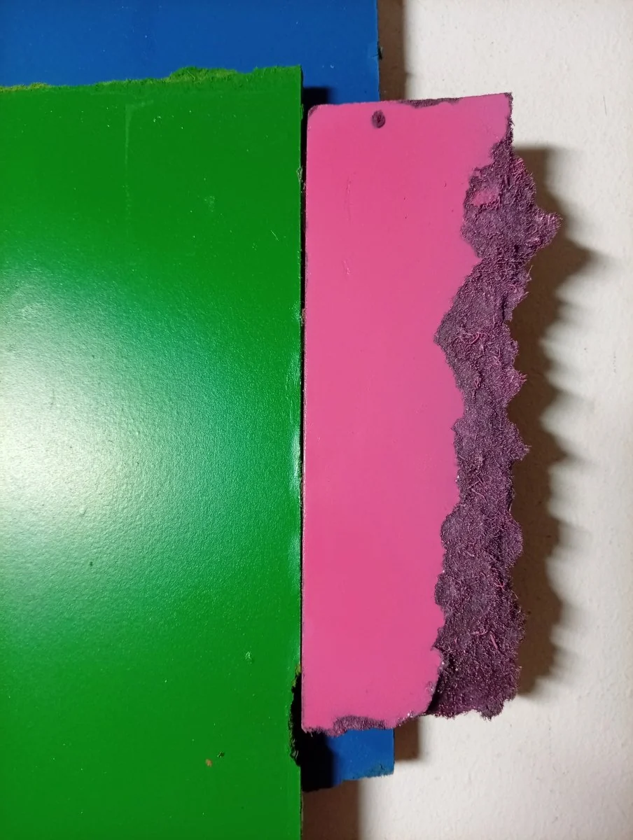 A layered composition of three rectangular paper sheets in blue, green, and pink against a white background.