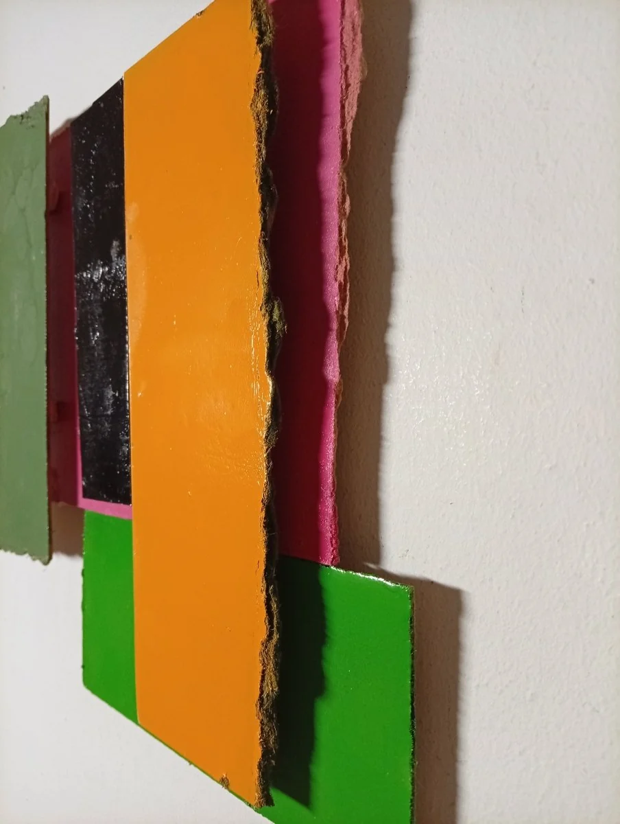A colorful abstract composition of layered rectangular blocks with torn edges.