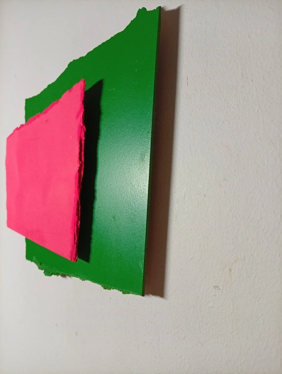 A layered composition of torn paper shapes in vivid pink and green against a white background.