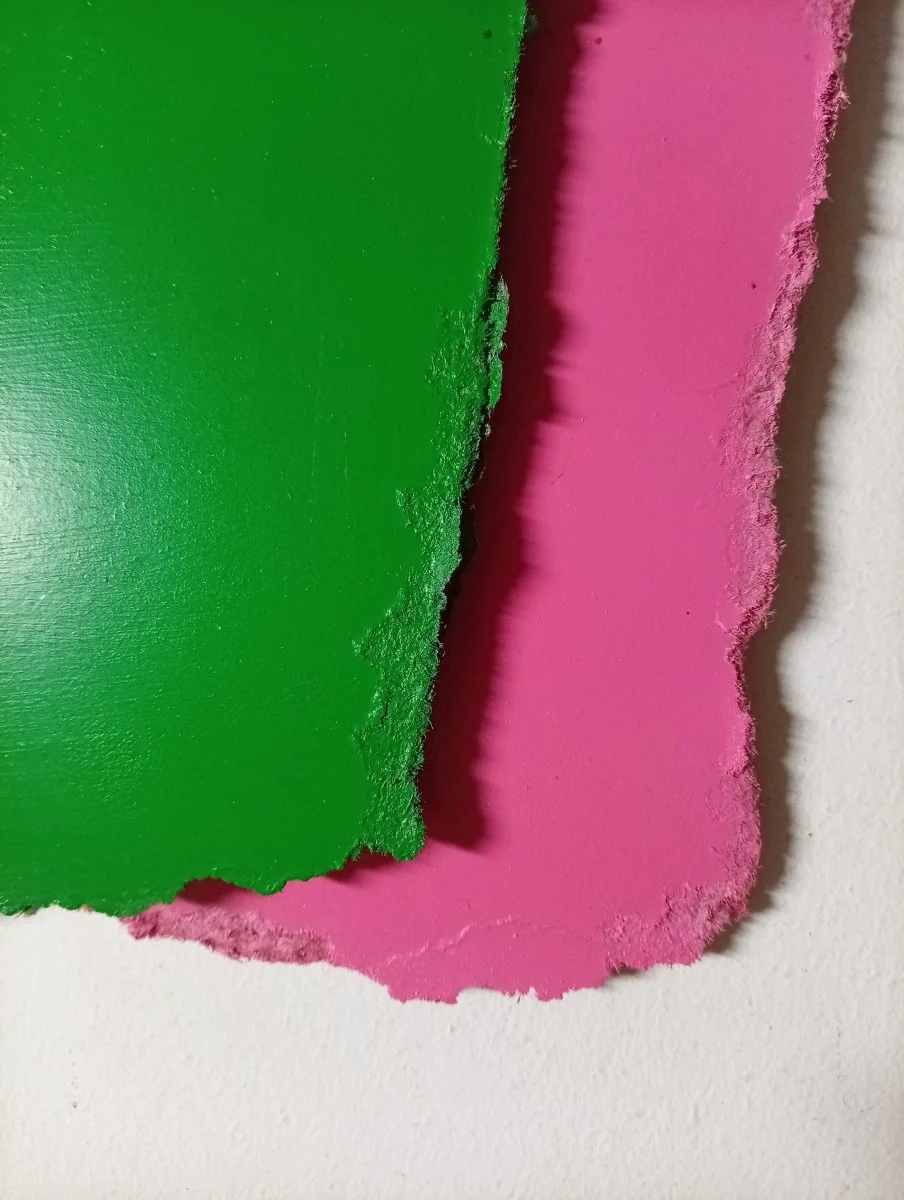 A layered composition of two textured, hand-cut paper sheets in contrasting colors.