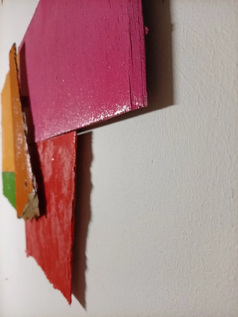 A colorful abstract composition of layered, torn rectangular shapes in primary and secondary colors.