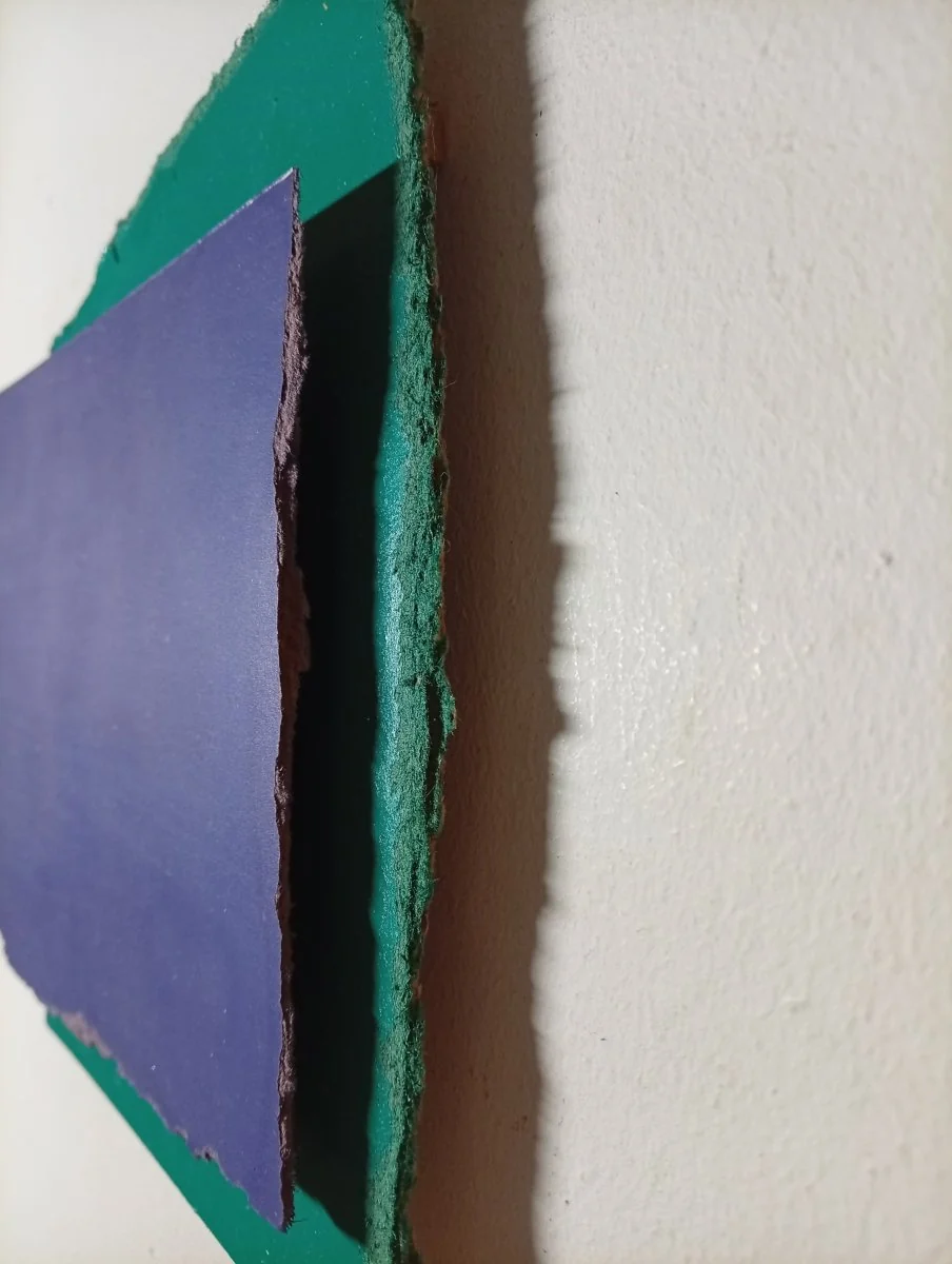 A layered composition of torn paper pieces in deep blue and forest green.