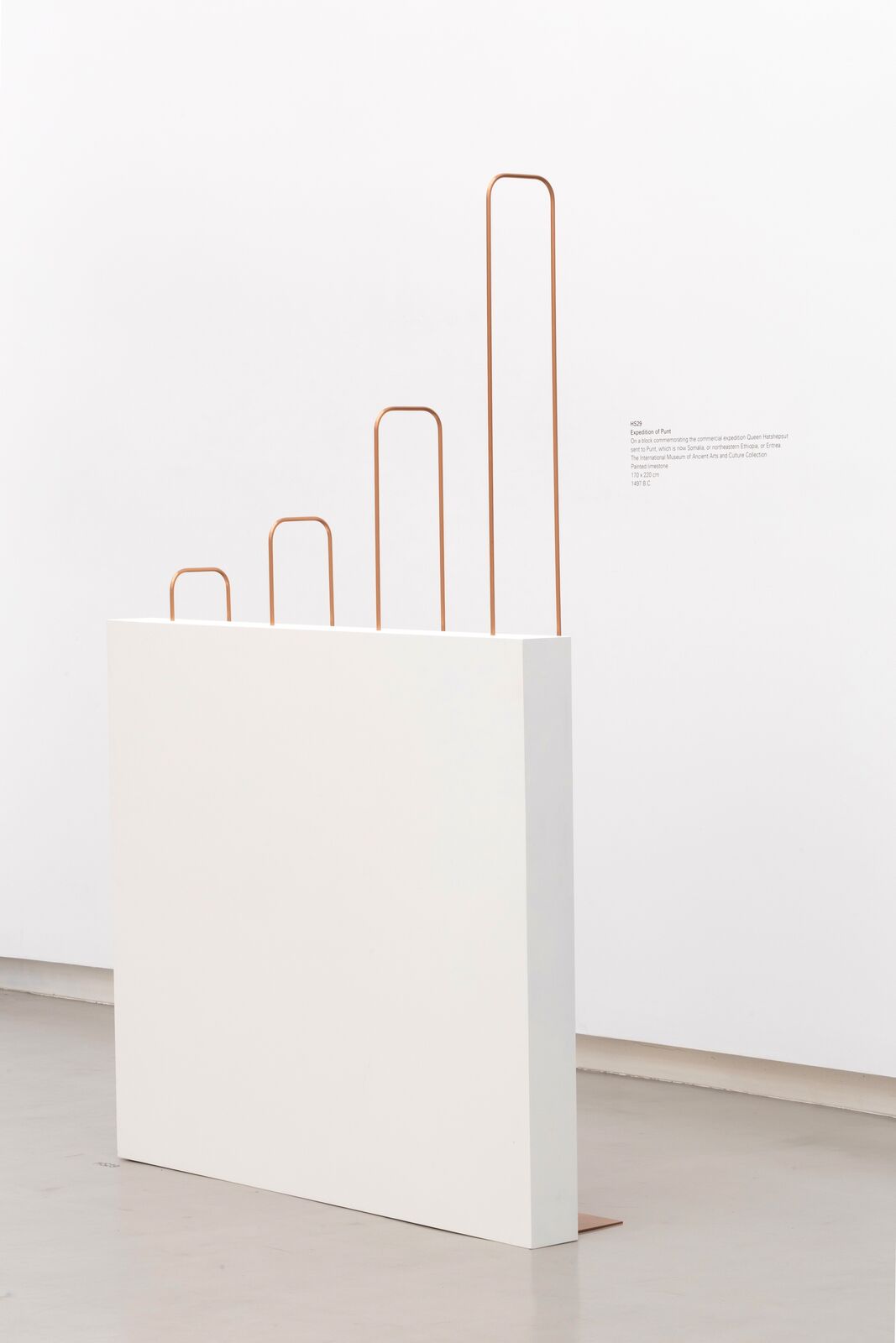 A white pedestal with three copper handles on top of it.
