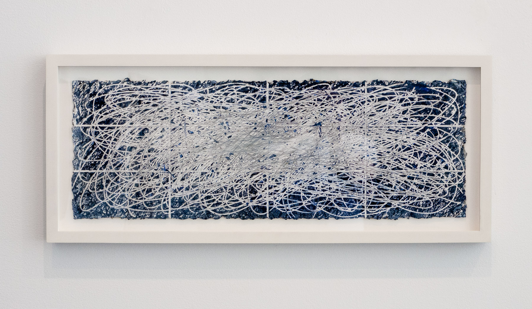 A framed abstract piece featuring a chaotic web of white lines over a dark blue textured background.