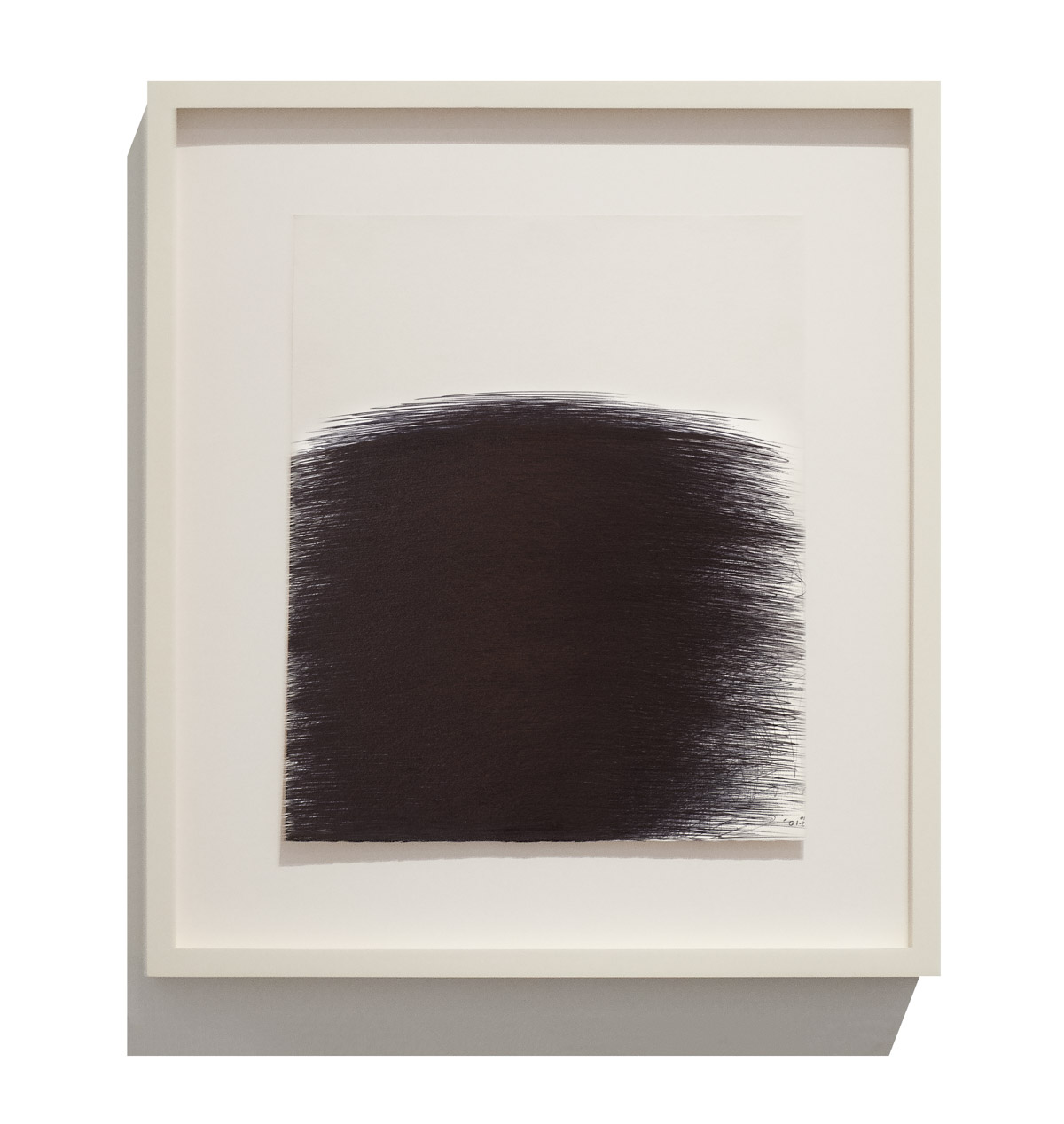 A minimalist framed artwork featuring a large, dark, textured shape against a stark white background.