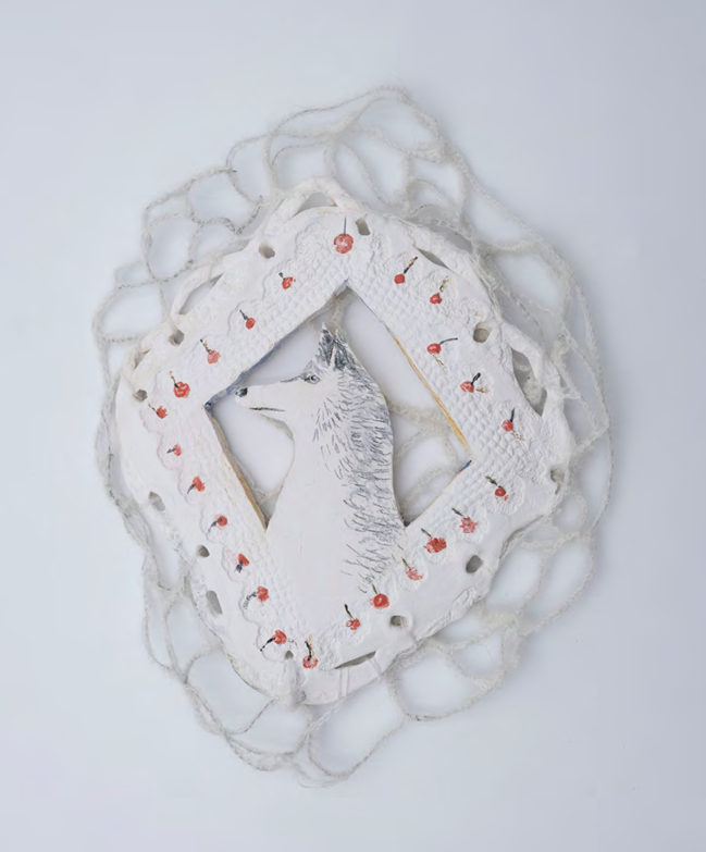 A white ceramic dog head surrounded by a string net with red berry decorations.