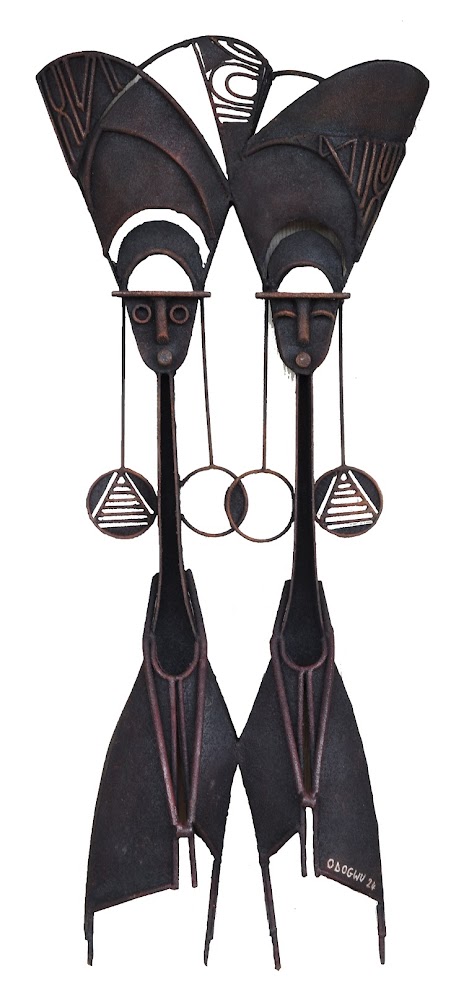 A symmetrical metal sculpture featuring two stylized figures with elongated necks and wing-like heads.