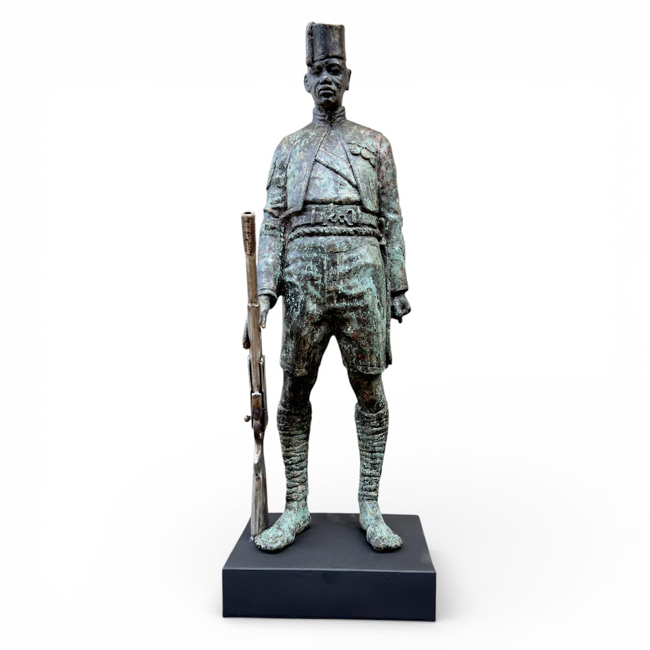 A bronze statue of a soldier in uniform holding a rifle.