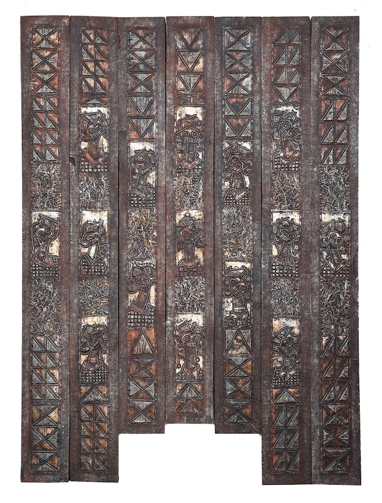 A rustic wooden panel featuring carved tribal figures and geometric patterns.