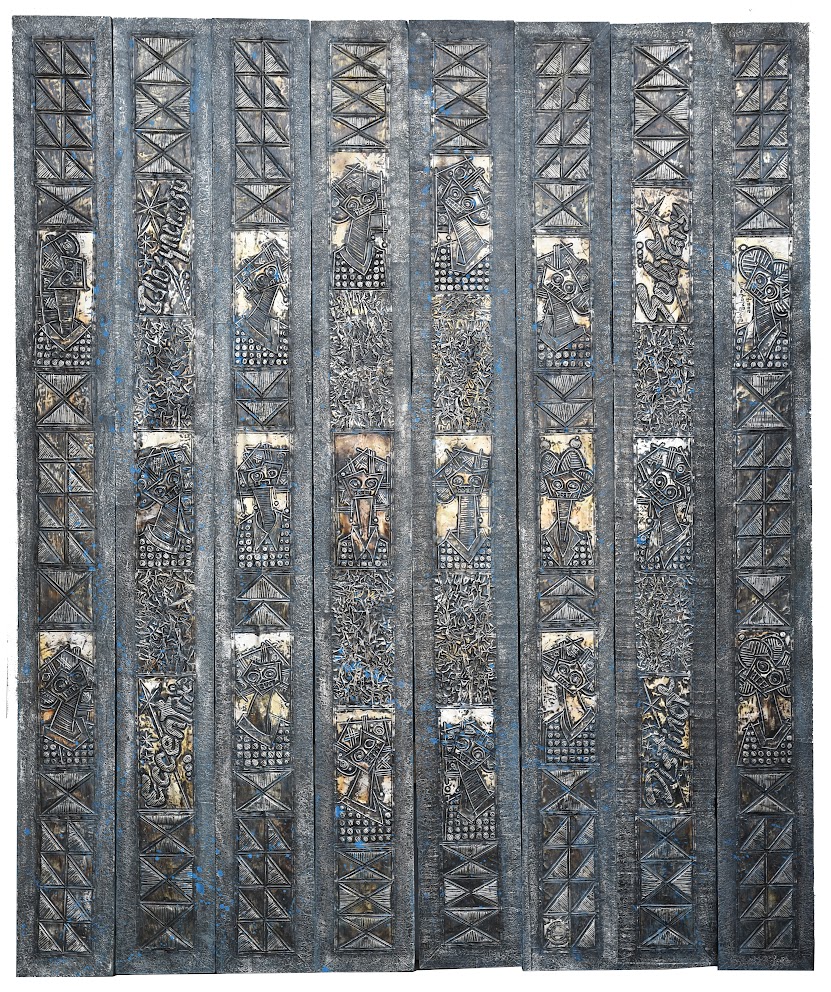 A vertical relief sculpture featuring nine narrow panels with carved geometric patterns and stylized figures.