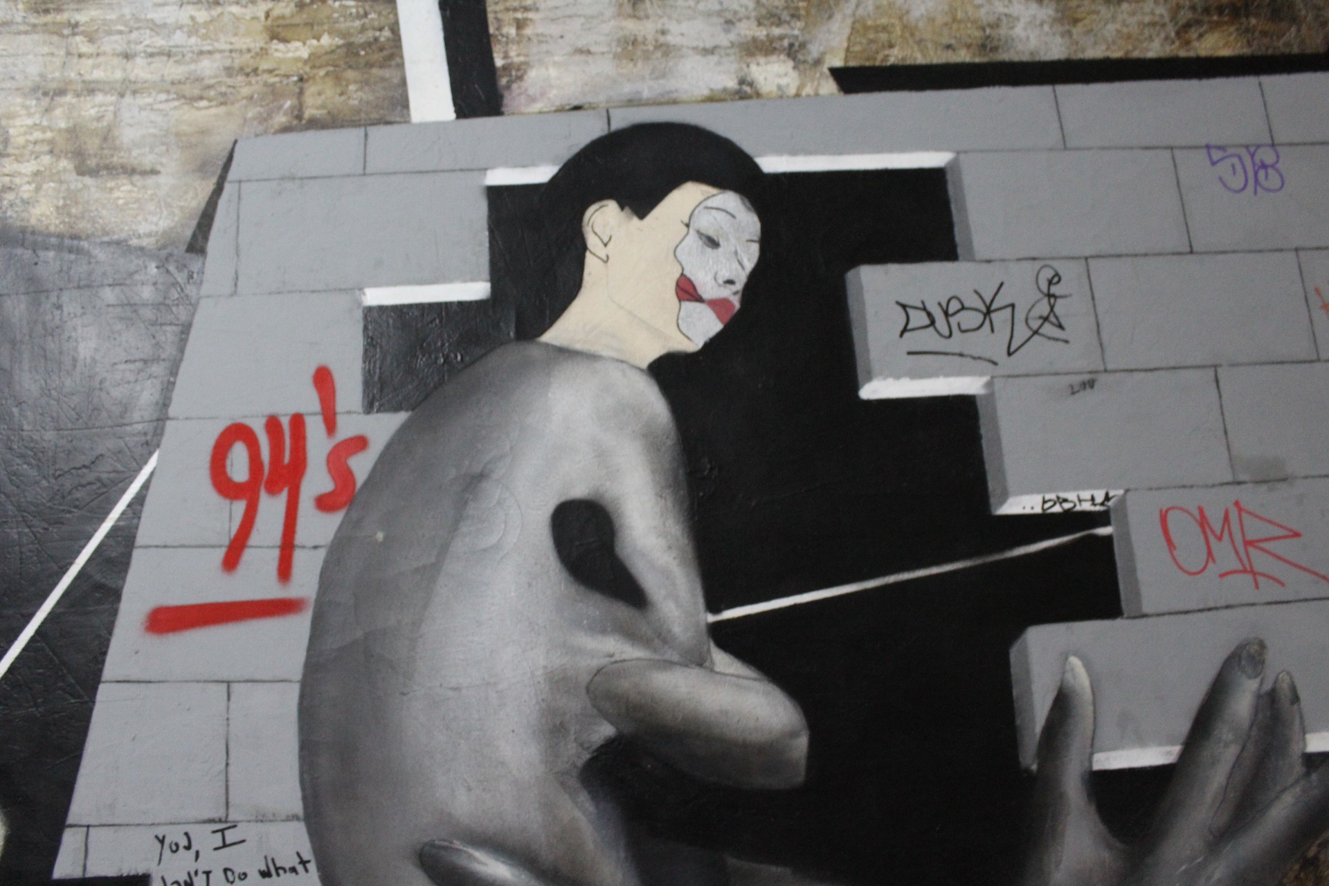 A painting of a hand on a wall with graffiti on it.